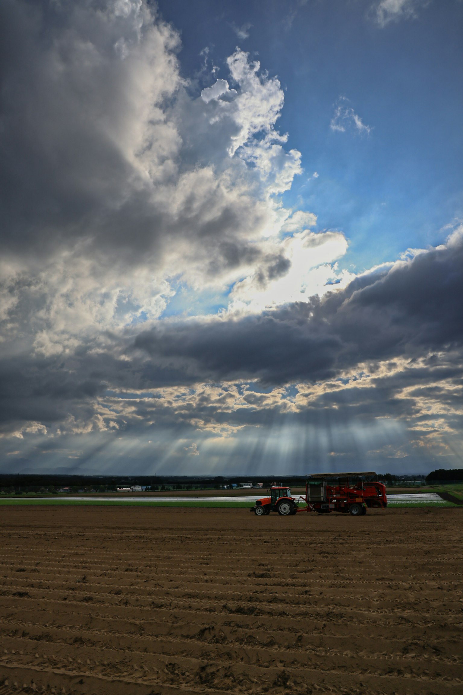 Traktor arbeitet auf einem Feld unter einem bewölkten Himmel
