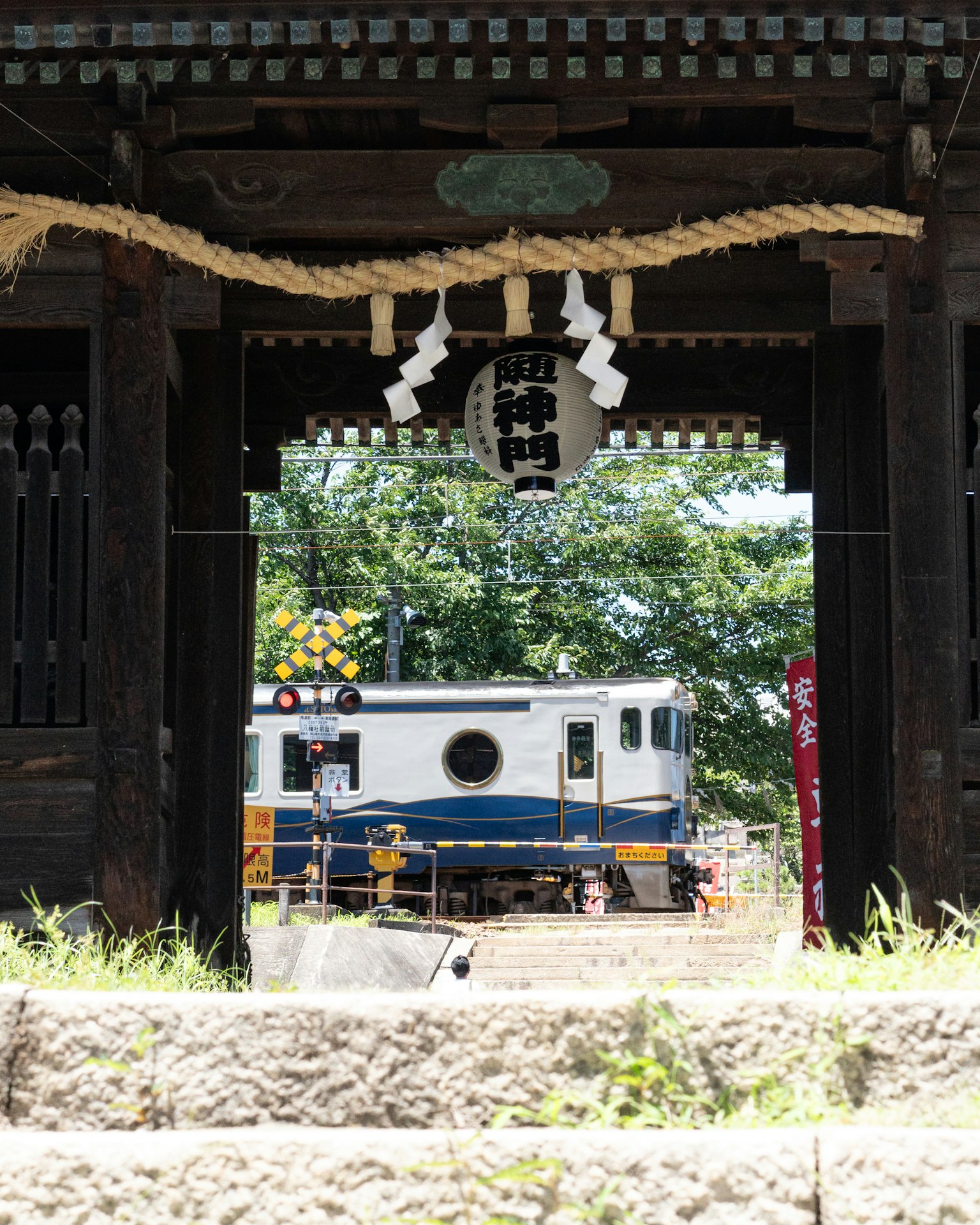 View of a train and greenery through an ancient shrine gate