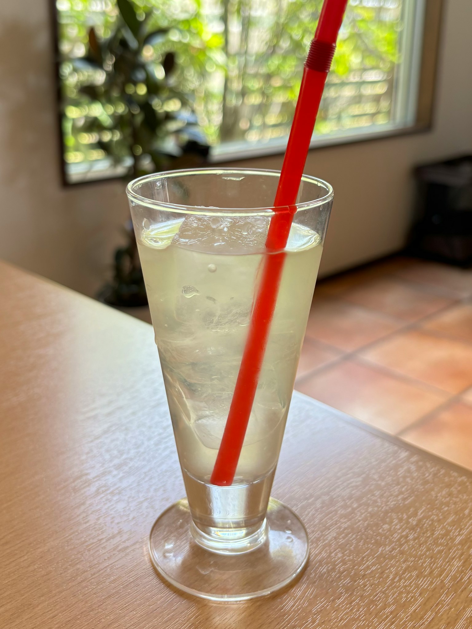 A clear drink in a glass with a red straw