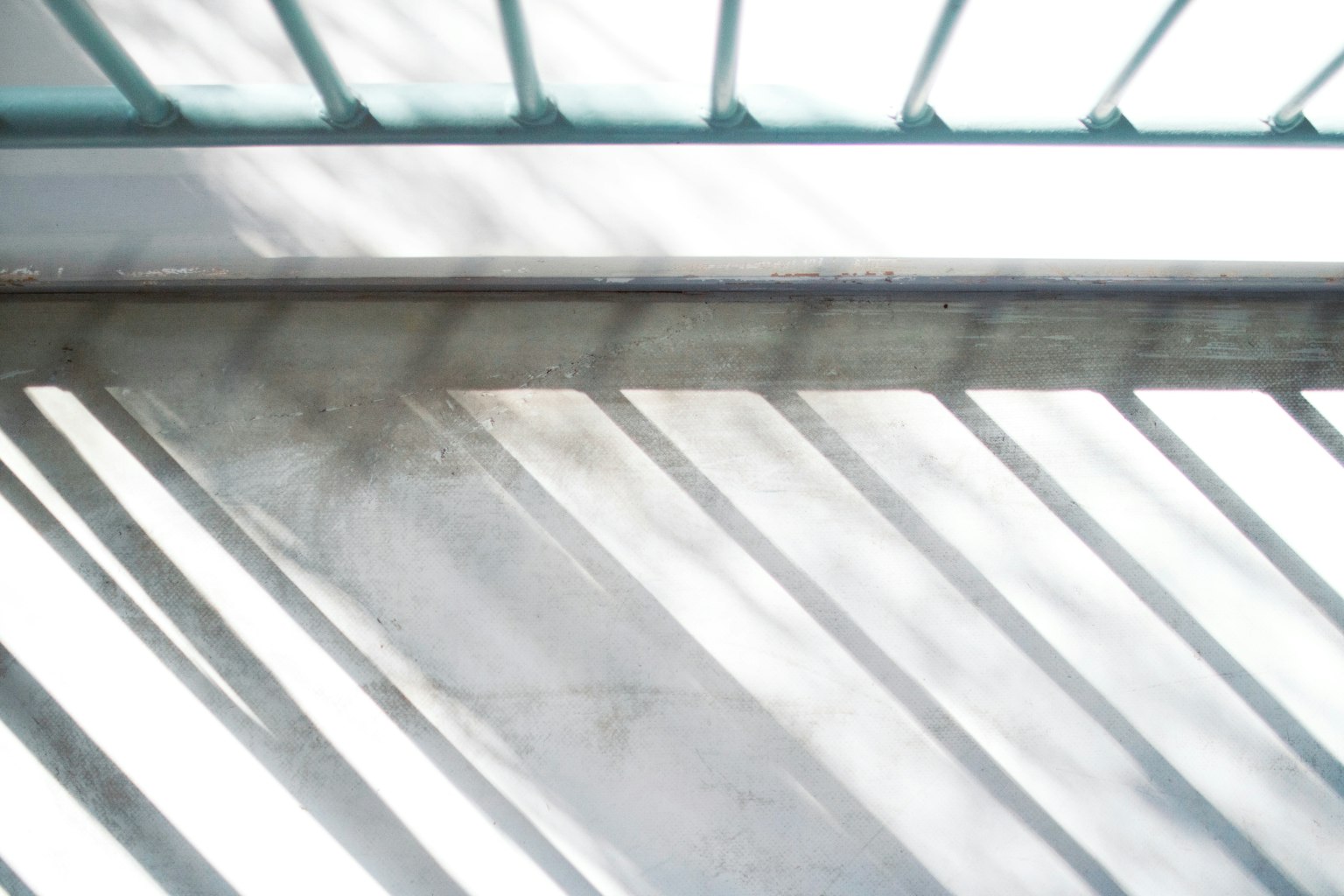 Sol en béton avec des ombres projetées par des barreaux de fenêtre et une lumière vive