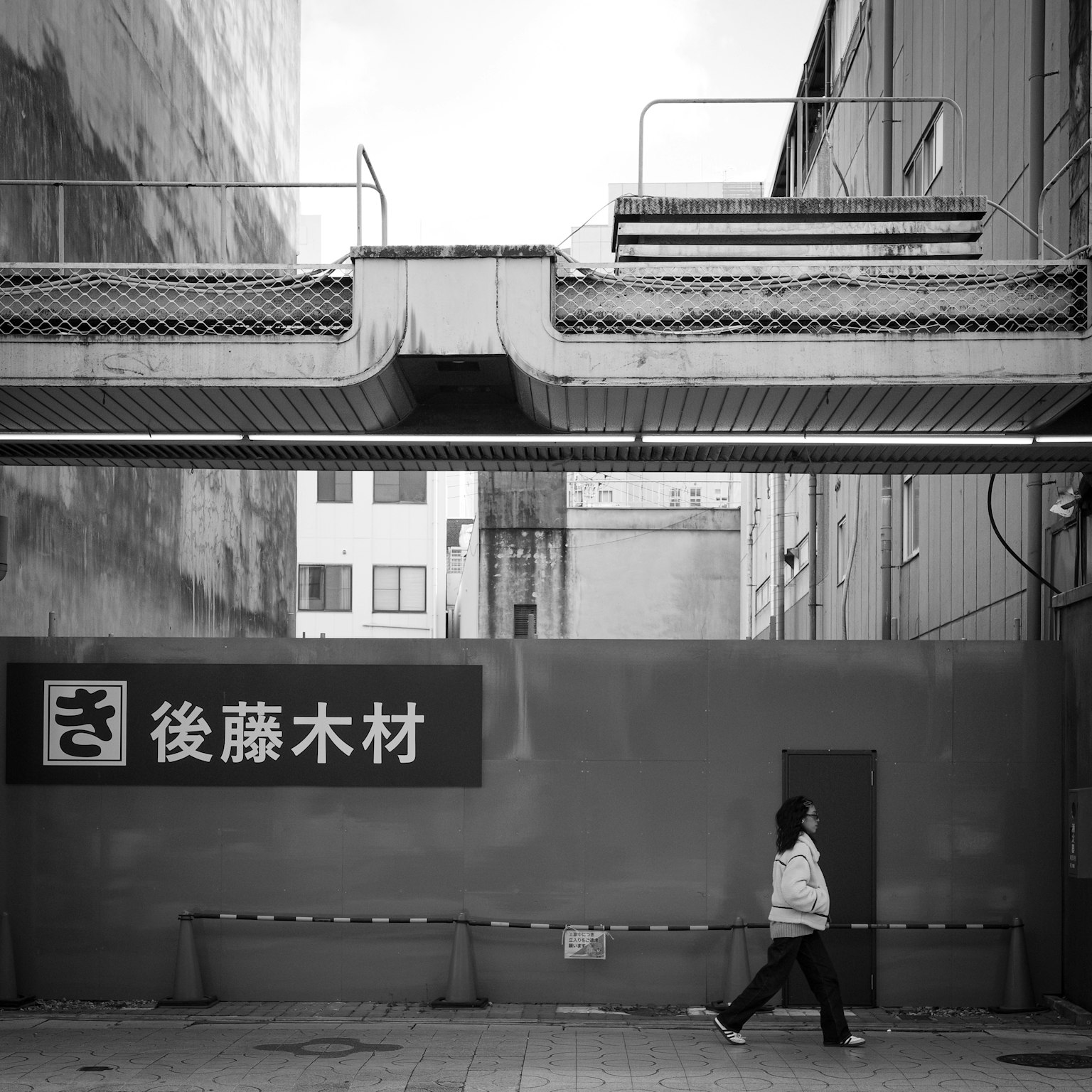 黑白城市景观，有人走过和一个标志