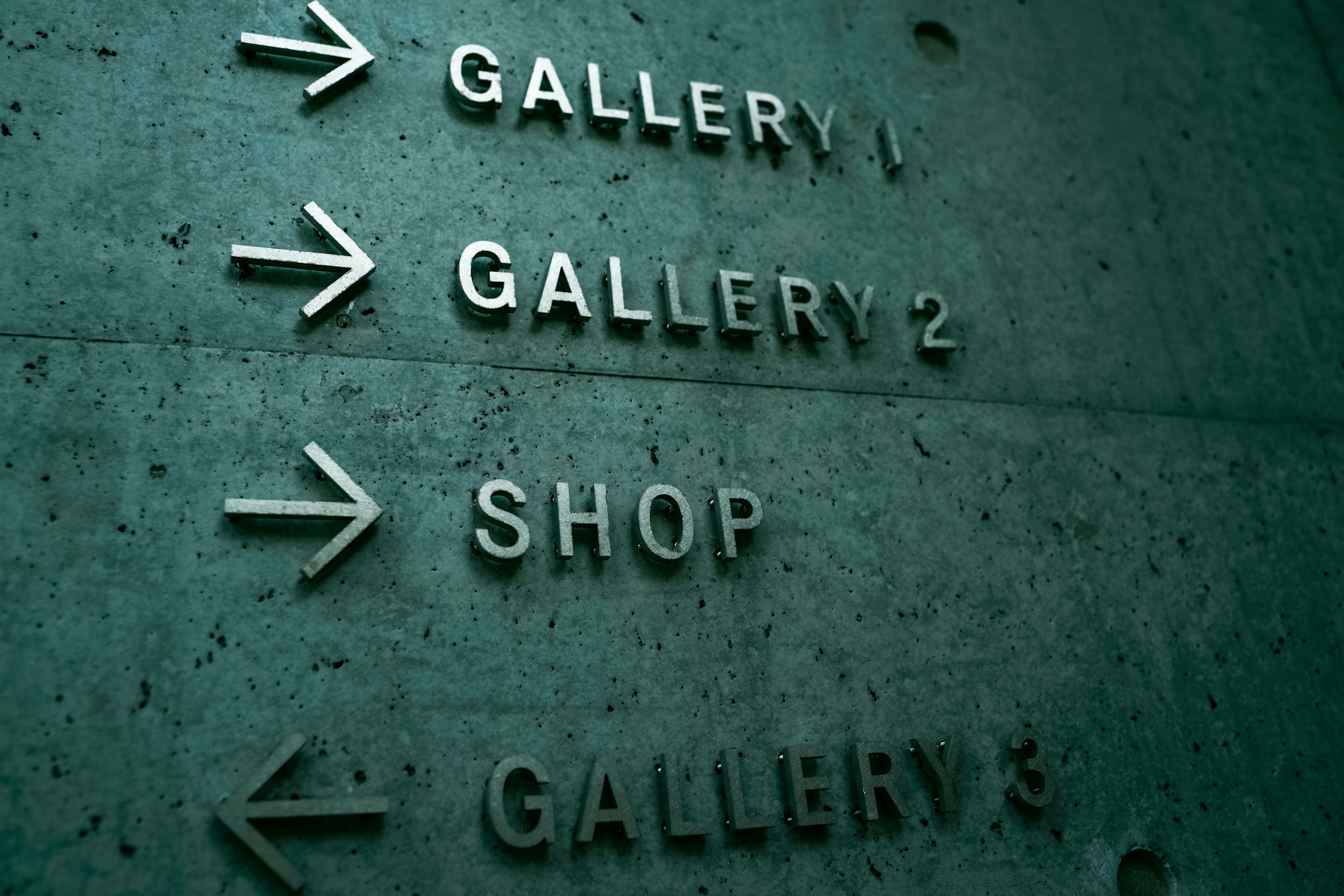 帶箭頭的牆面指示牌，上面寫著「GALLERY」和「SHOP」