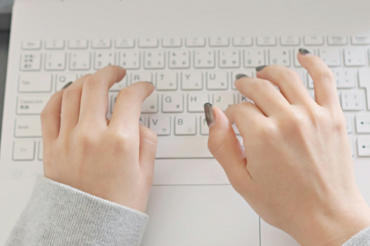 Primer plano de manos escribiendo en un teclado de portátil