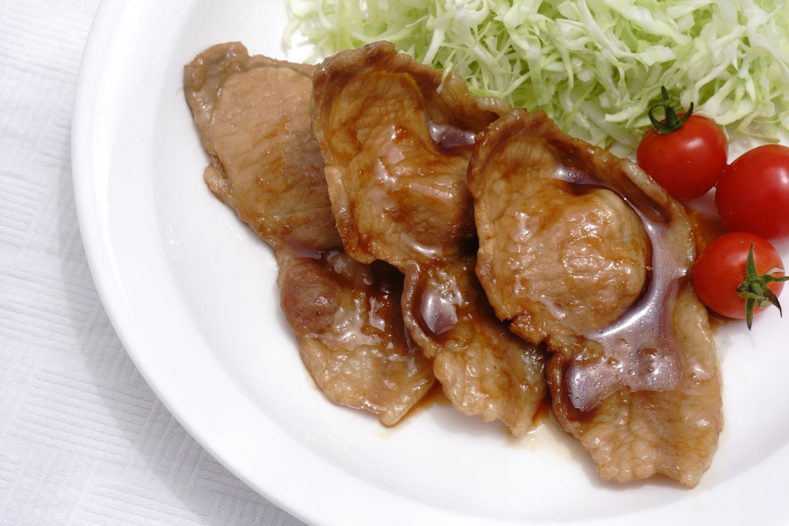 Schweinefleischscheiben mit Kohl und Kirschtomaten auf einem Teller