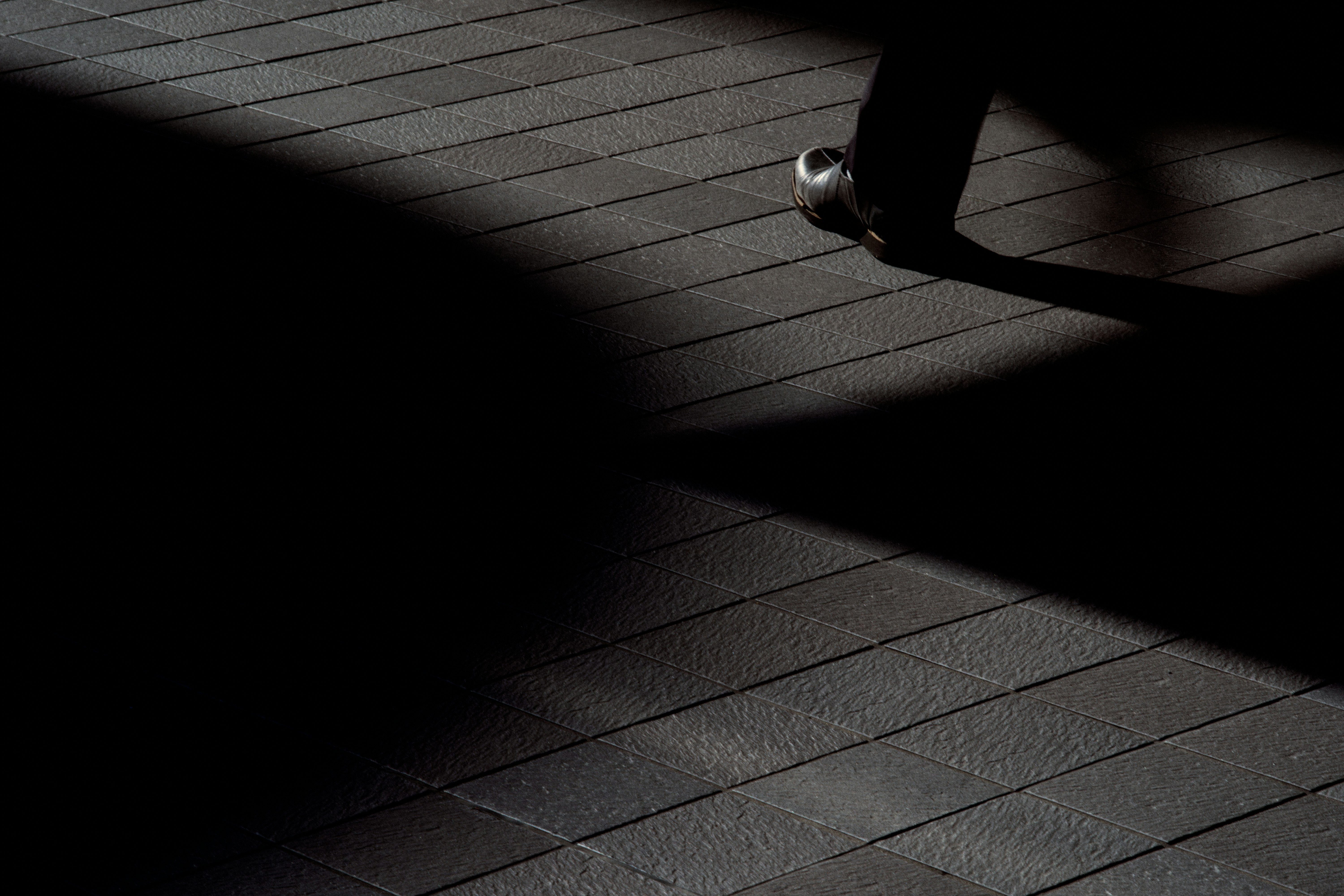 shoe toe on a tiled floor with strong shadows