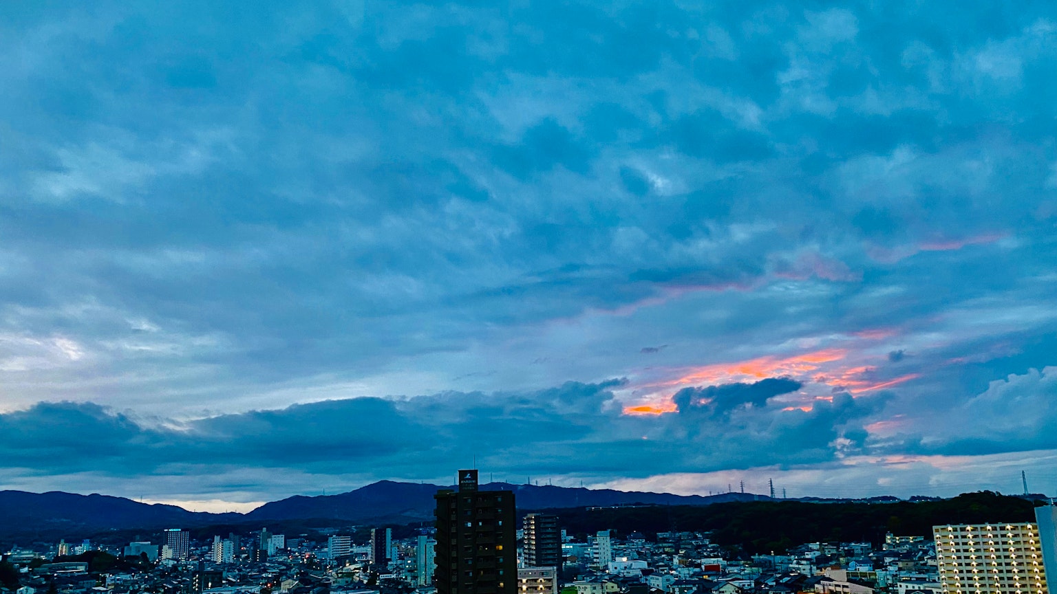 Paysage urbain sous un ciel bleu avec des nuages silhouette de montagnes en arrière-plan