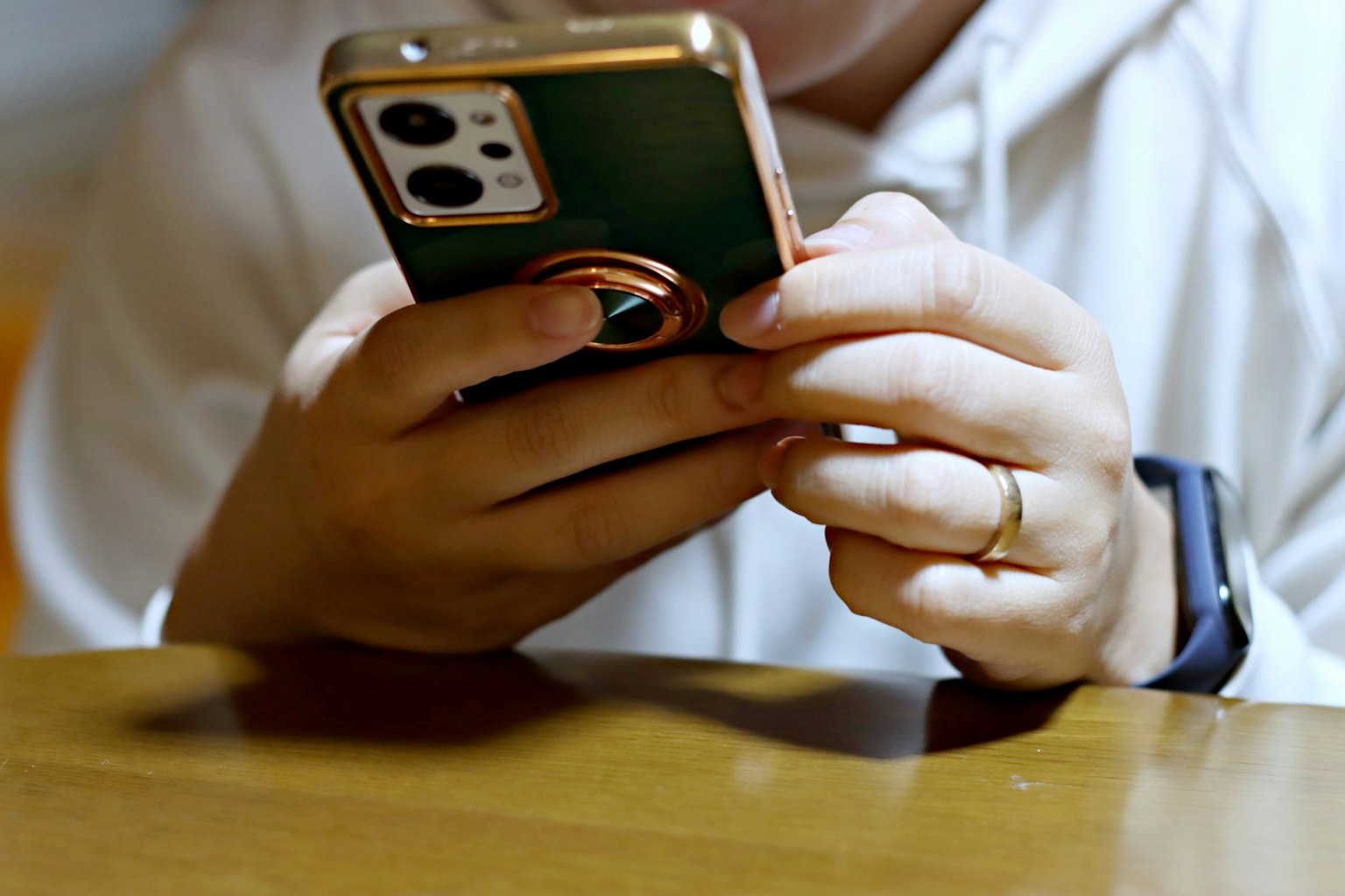 Mains tenant un smartphone vert sur une table en bois