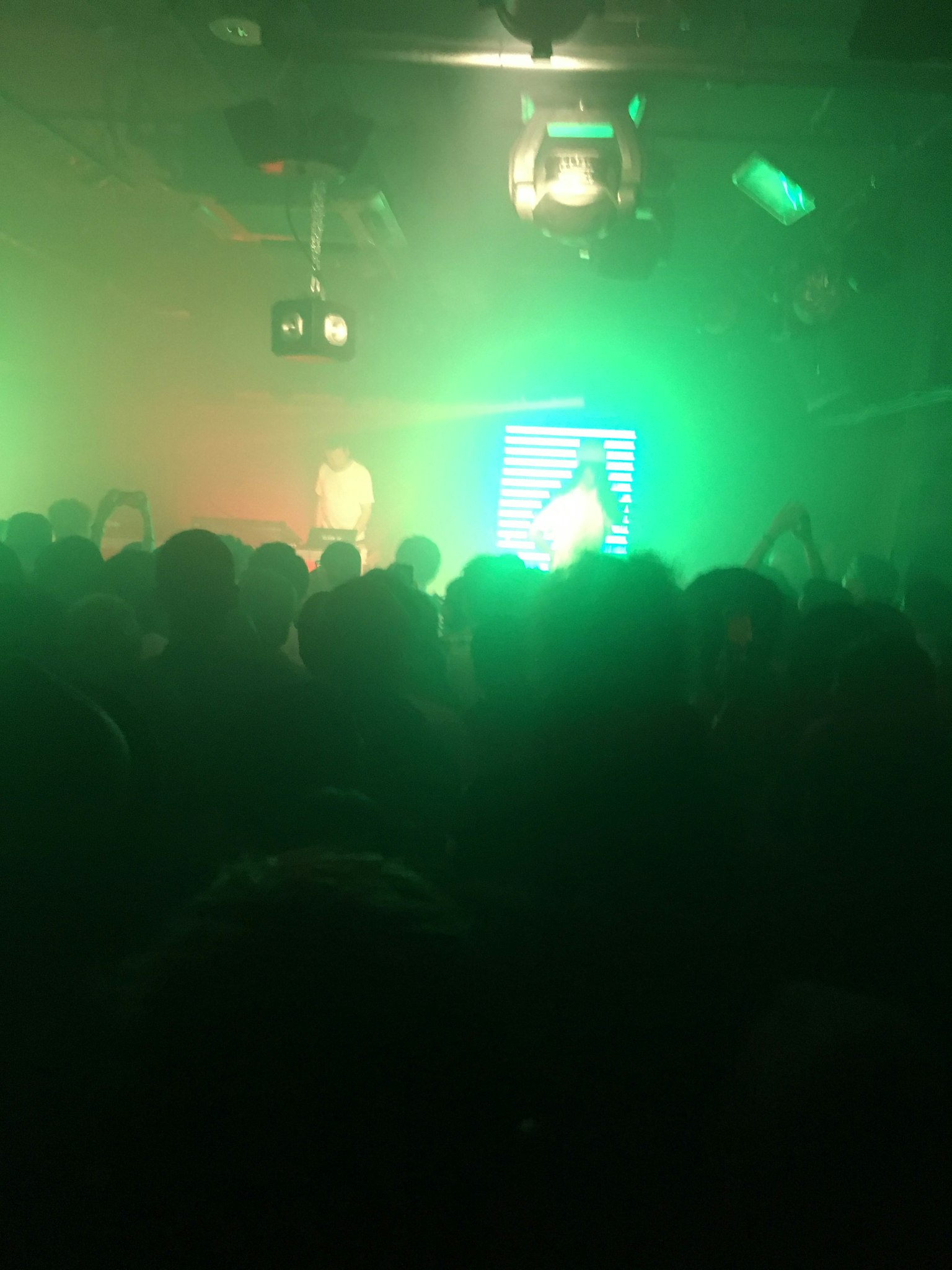 Foule appréciant une scène de club vibrante avec des lumières vertes et orange