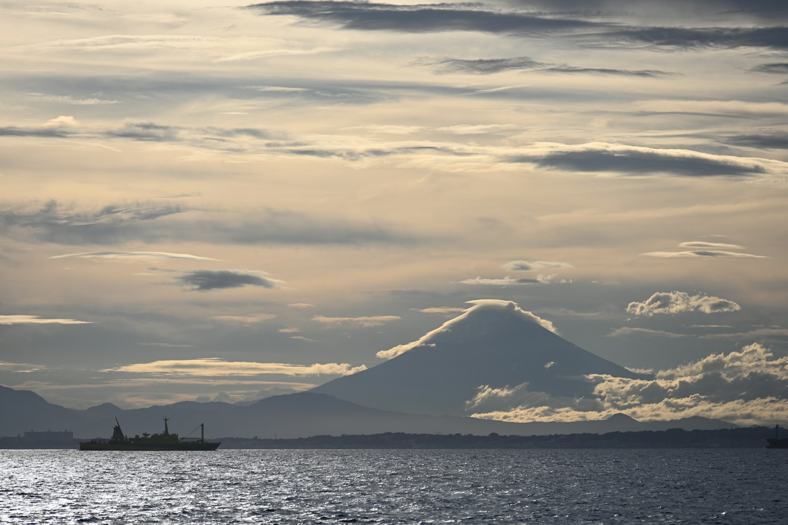 A distant view of a ship on the water with a mountain in the background