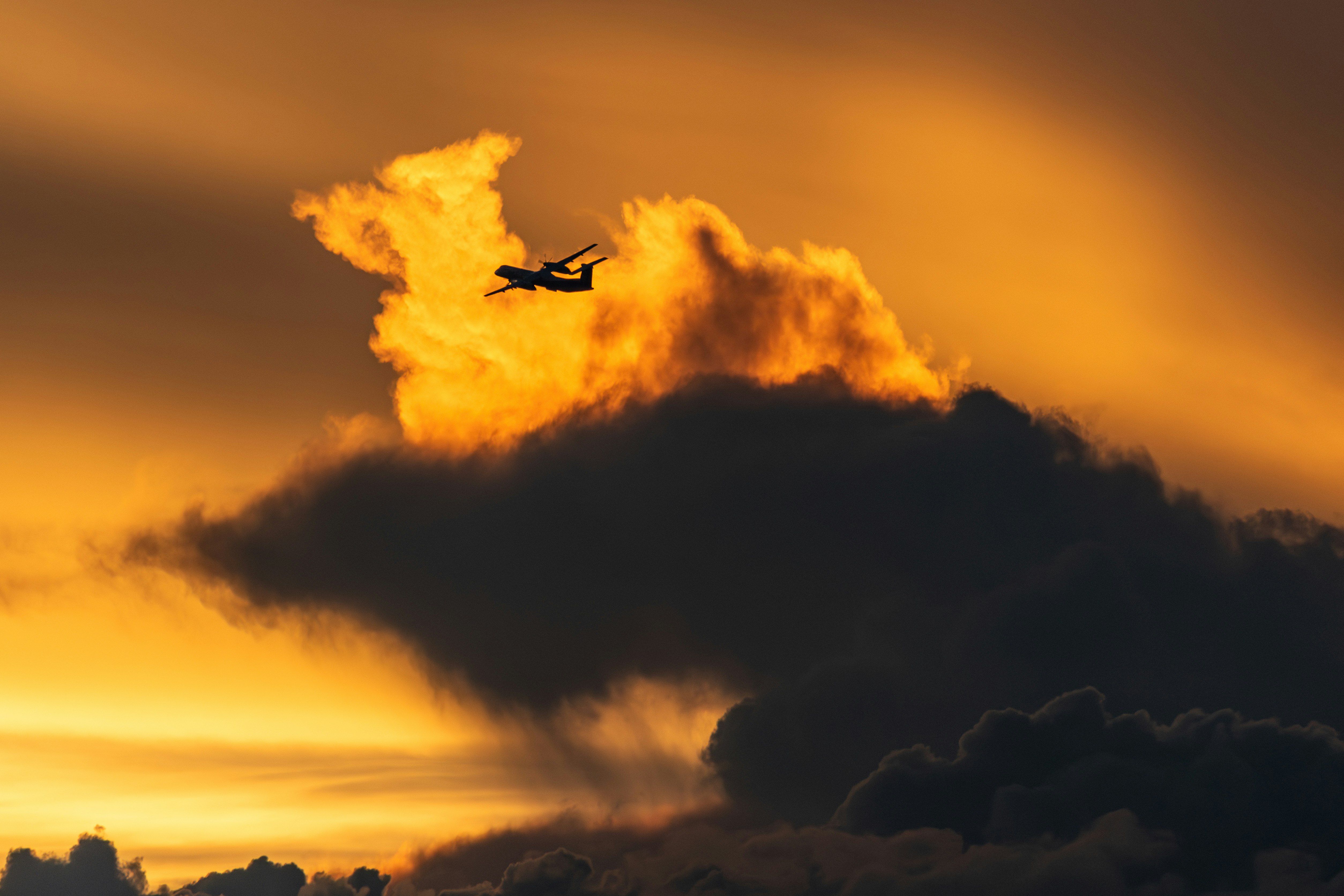 夕日に染まる雲と飛行機が入る空の風景
