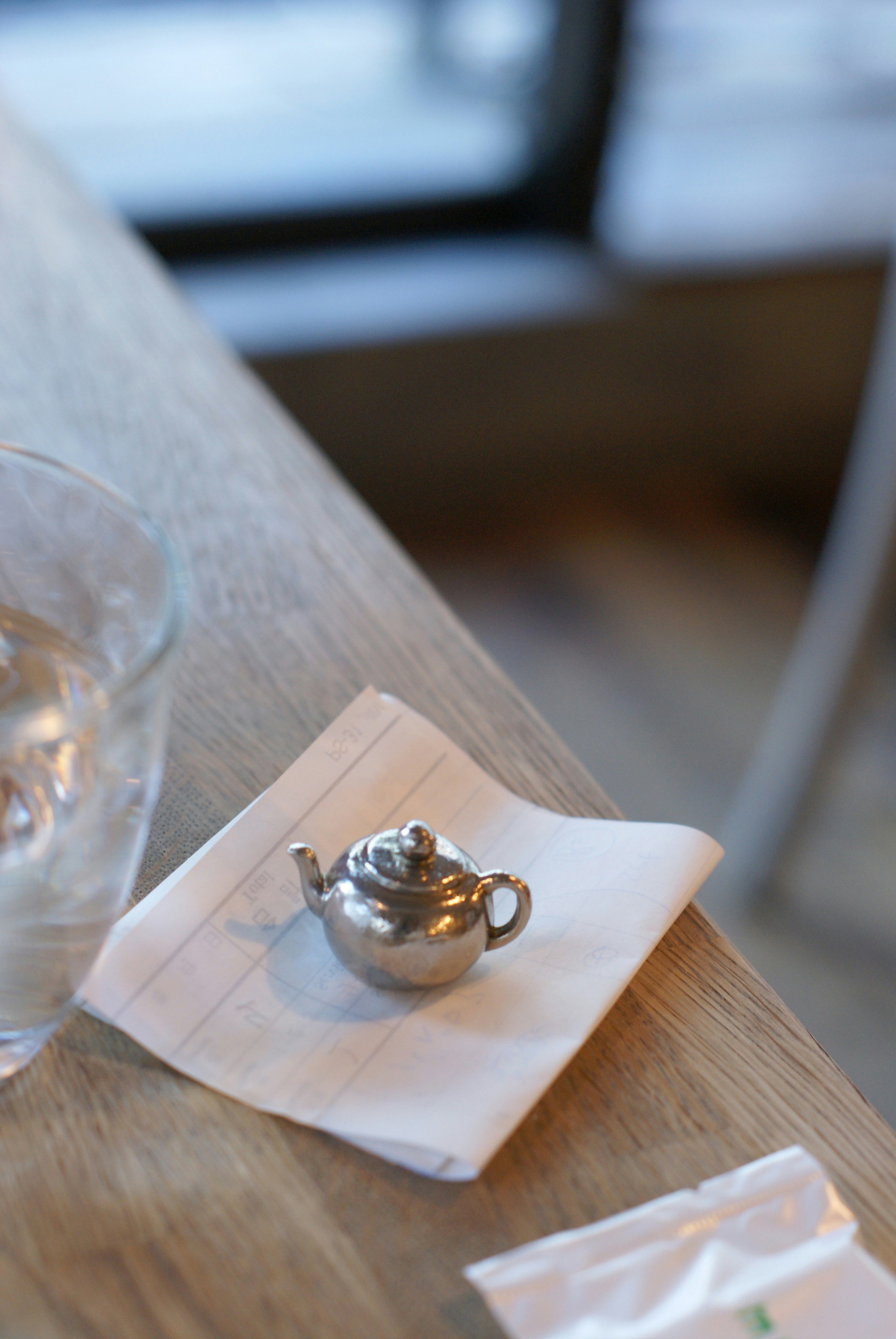 small silver teapot on a wooden table with a folded napkin