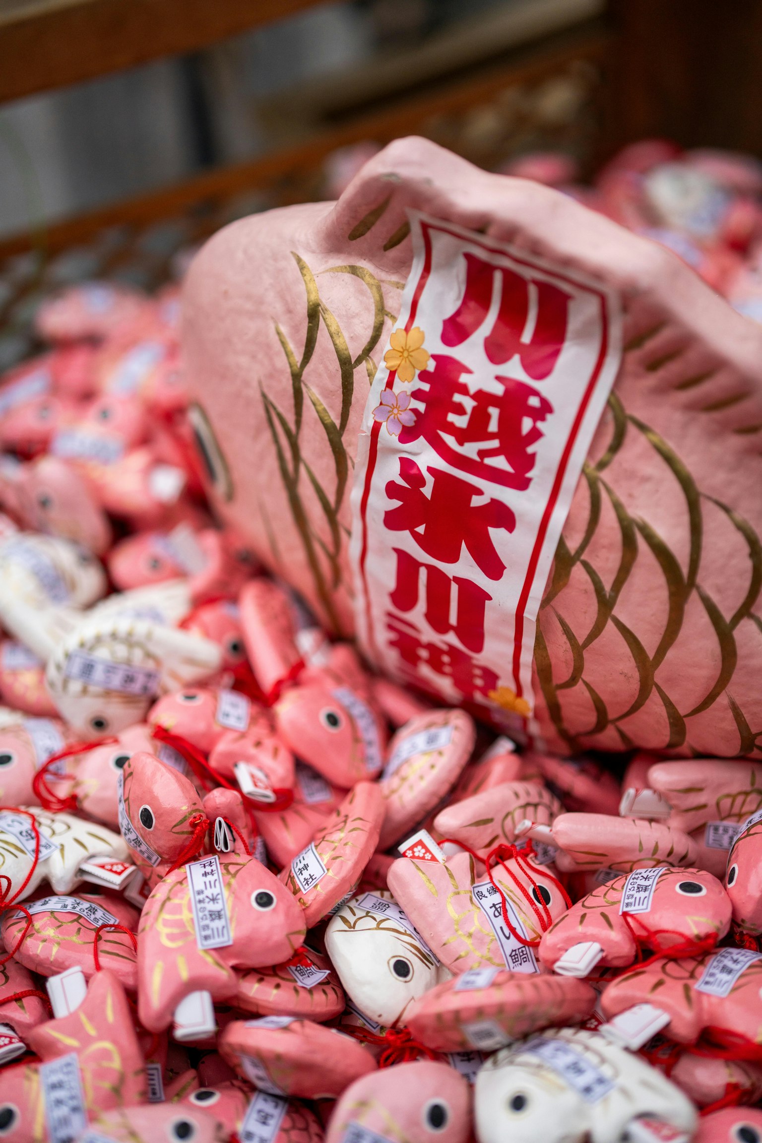 Mainan ikan besar berwarna pink dengan tulisan merah dikelilingi oleh banyak mainan ikan kecil berwarna-warni