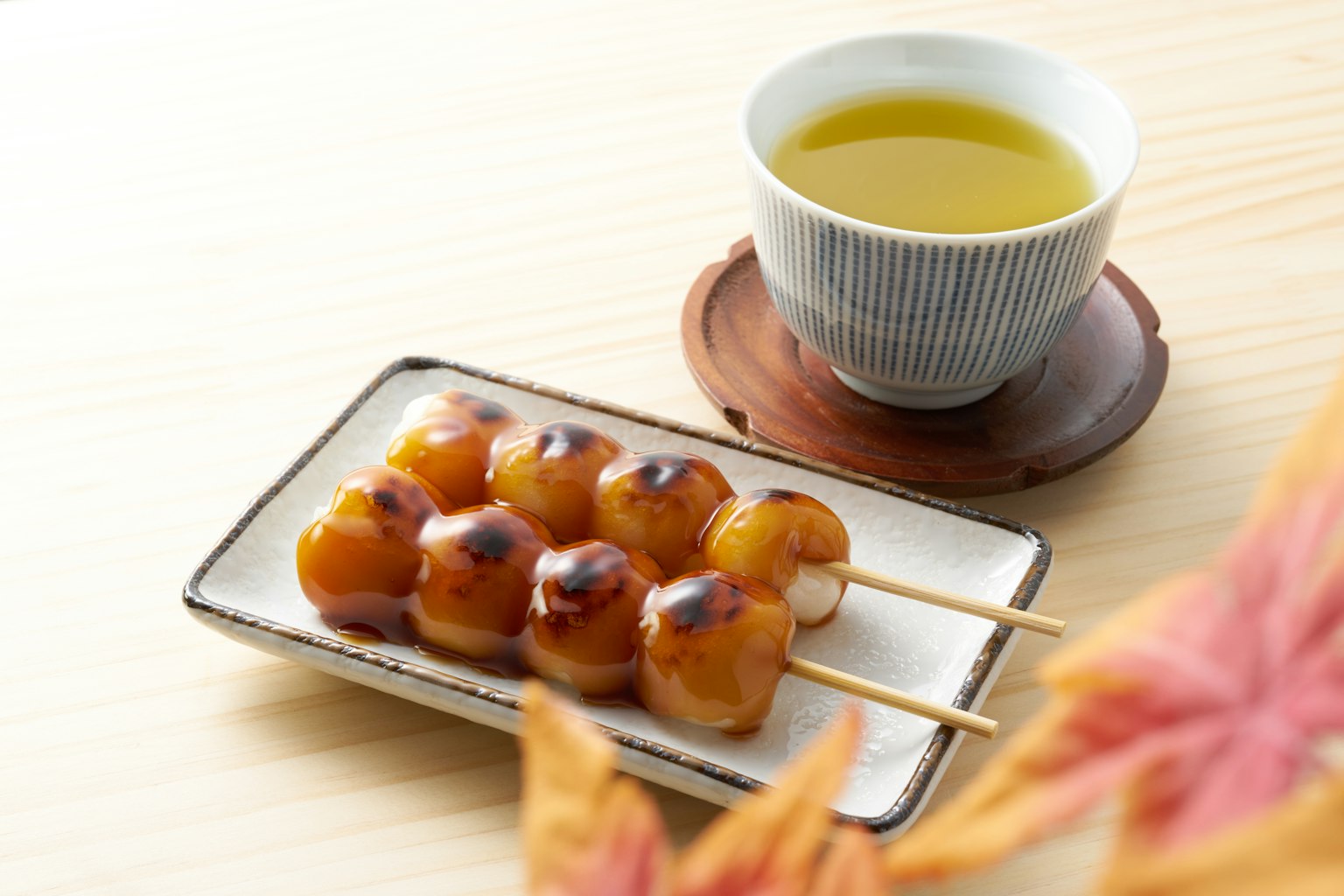 A plate of dango skewers served with a cup of green tea on a wooden table