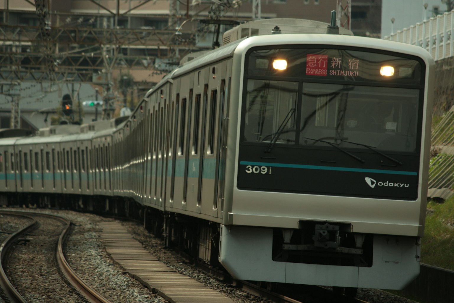 Treno su binari curvi con segnali di stazione visibili