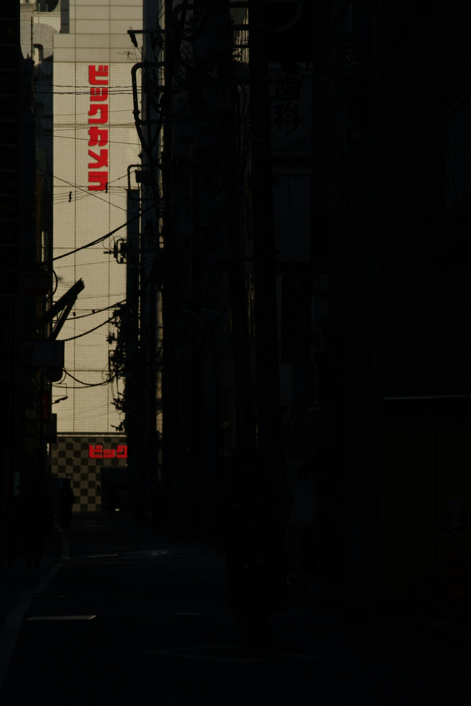 Silhouette of buildings and a sign in a dark alley