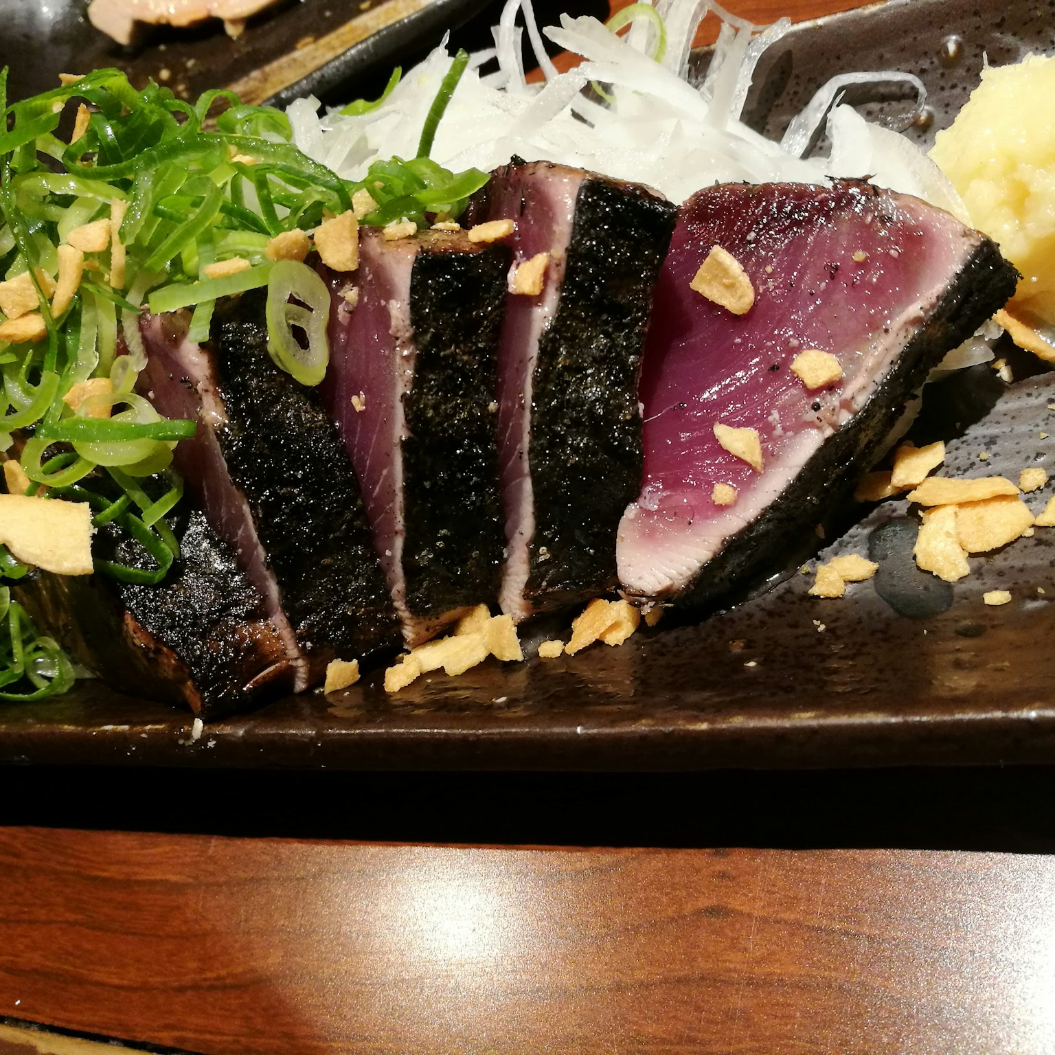 切片的新鲜金枪鱼刺身，配以装饰，放在盘子上