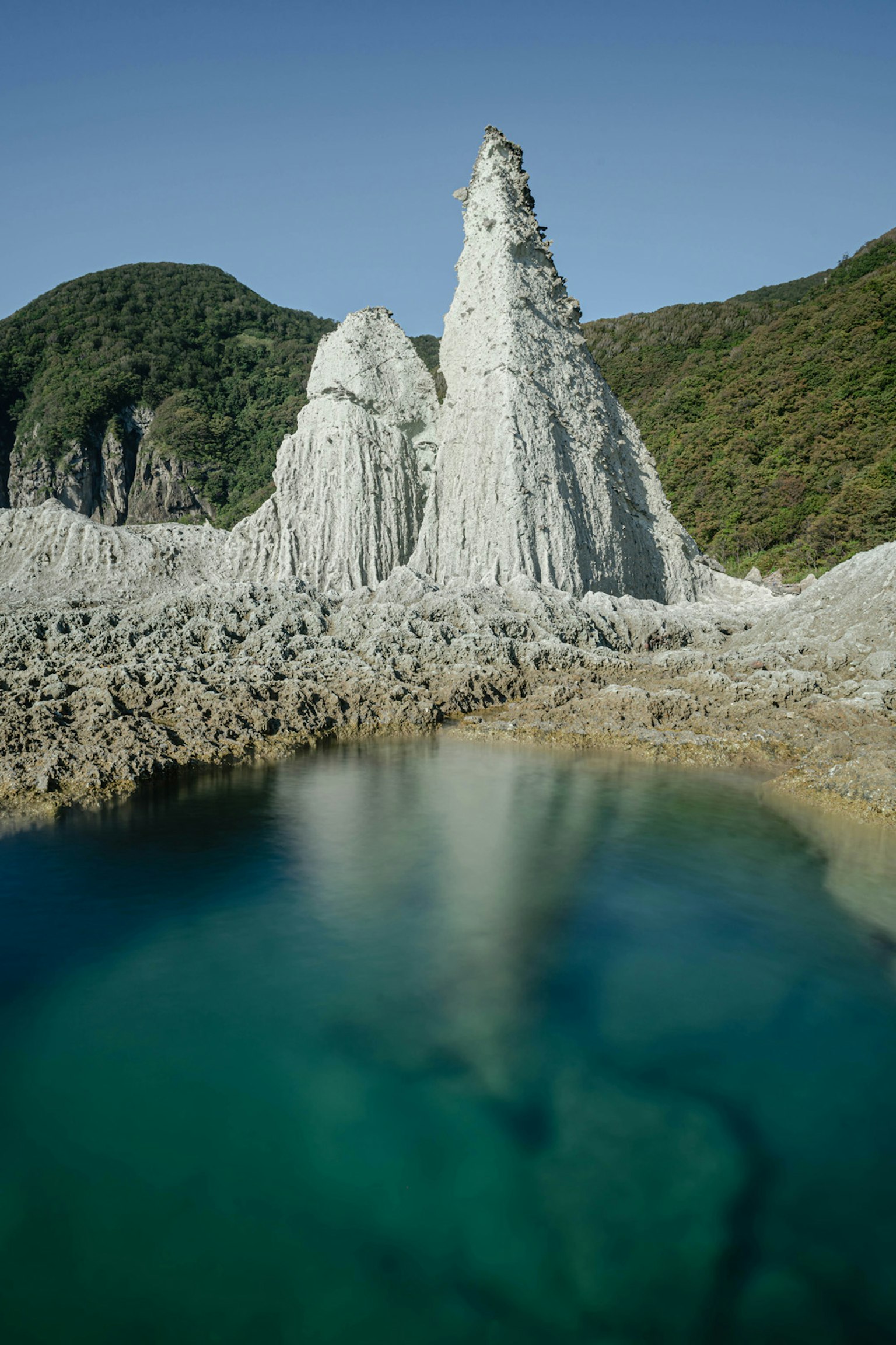 Vue pittoresque de formations rocheuses blanches entourées de collines verdoyantes et d'eau bleue claire