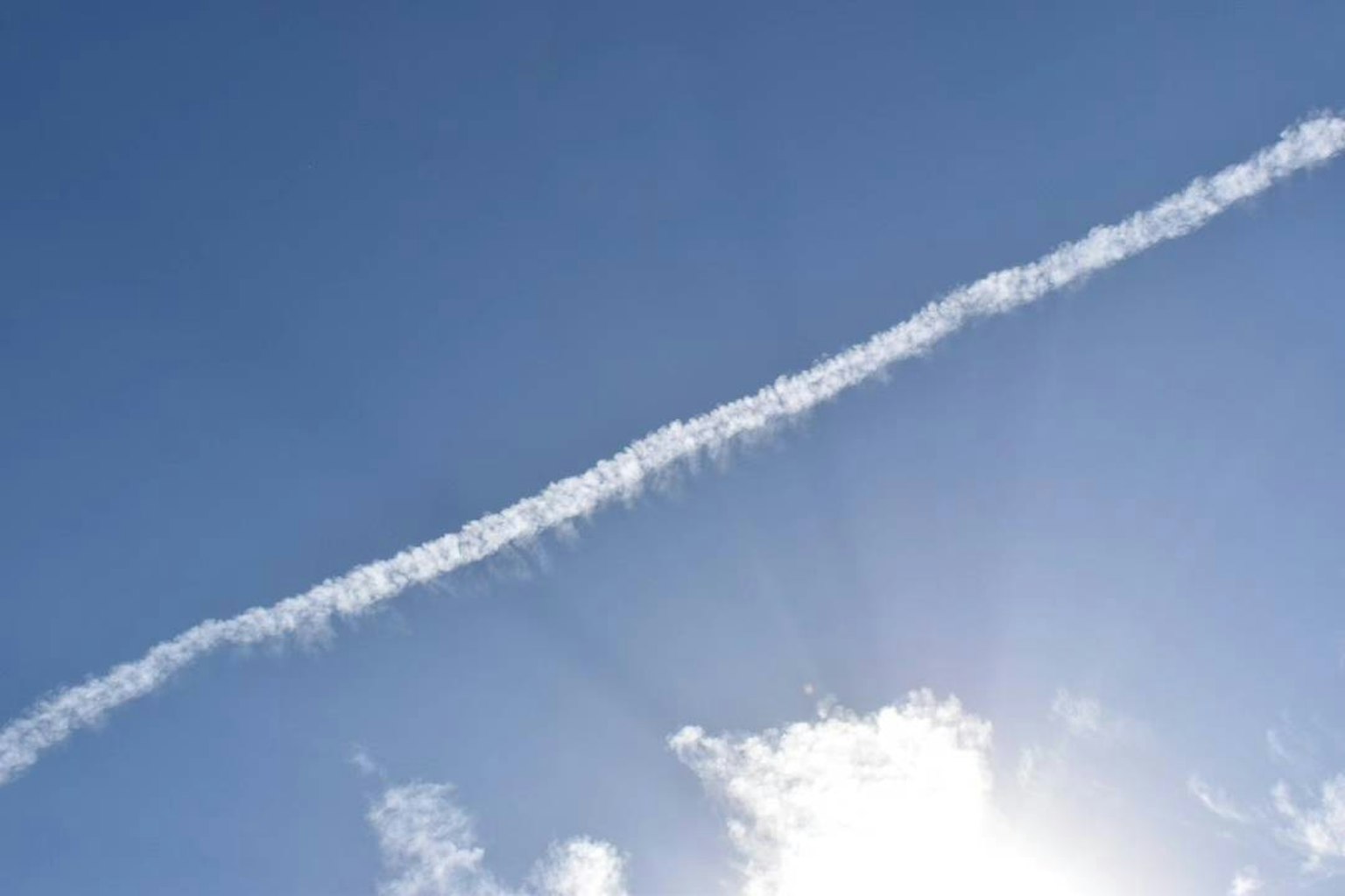 Estela blanca en cielo azul con luz solar