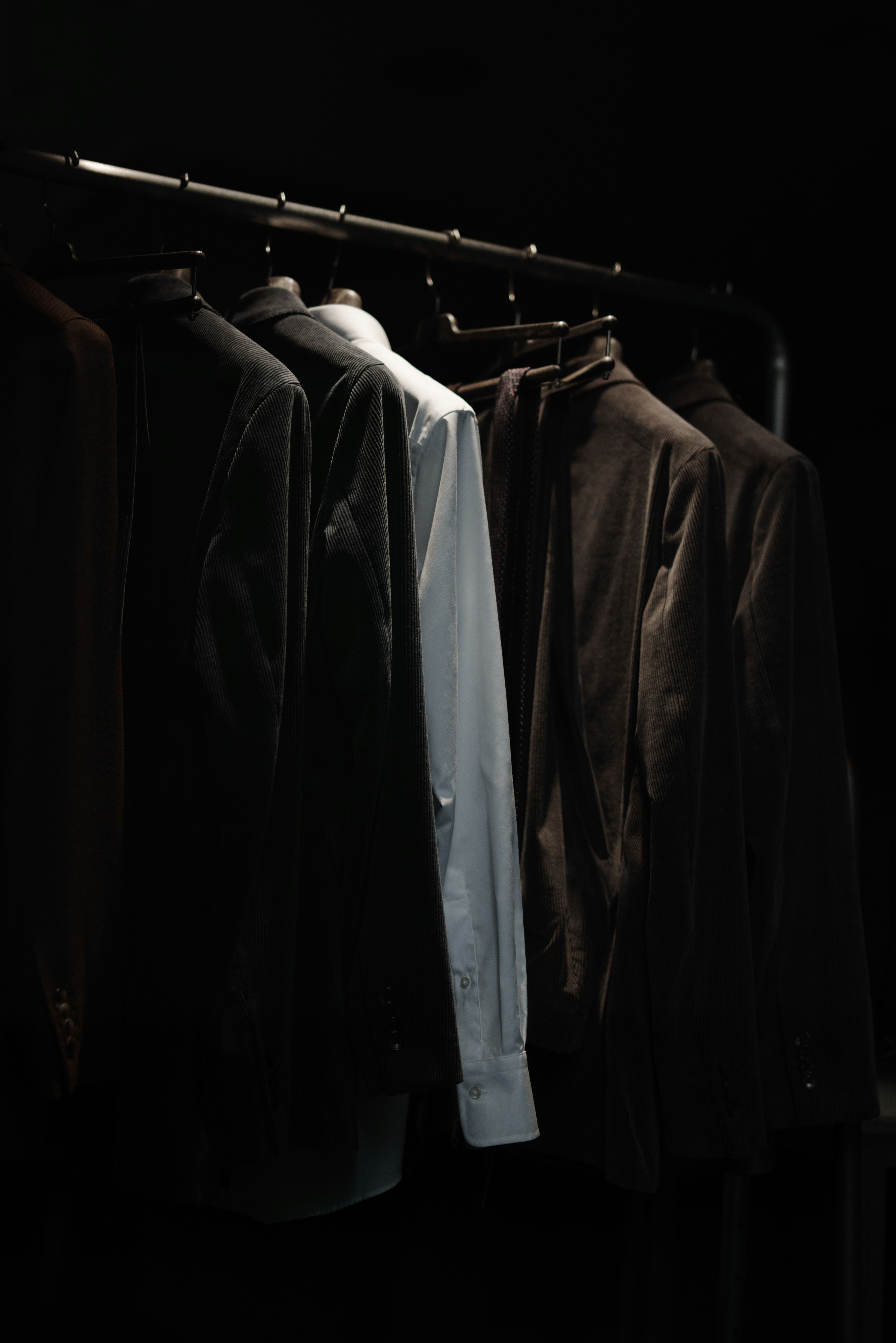 เสื้อผ้าที่แขวนบนราวในตู้เสื้อผ้าสลัว