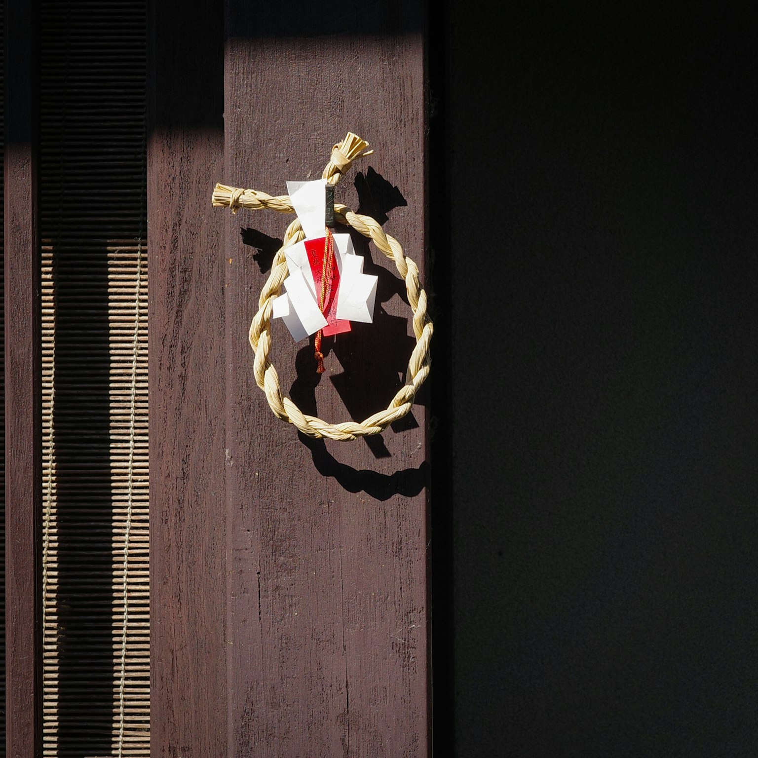 Decorazione ad anello di paglia intrecciata con carta bianca su una porta di legno