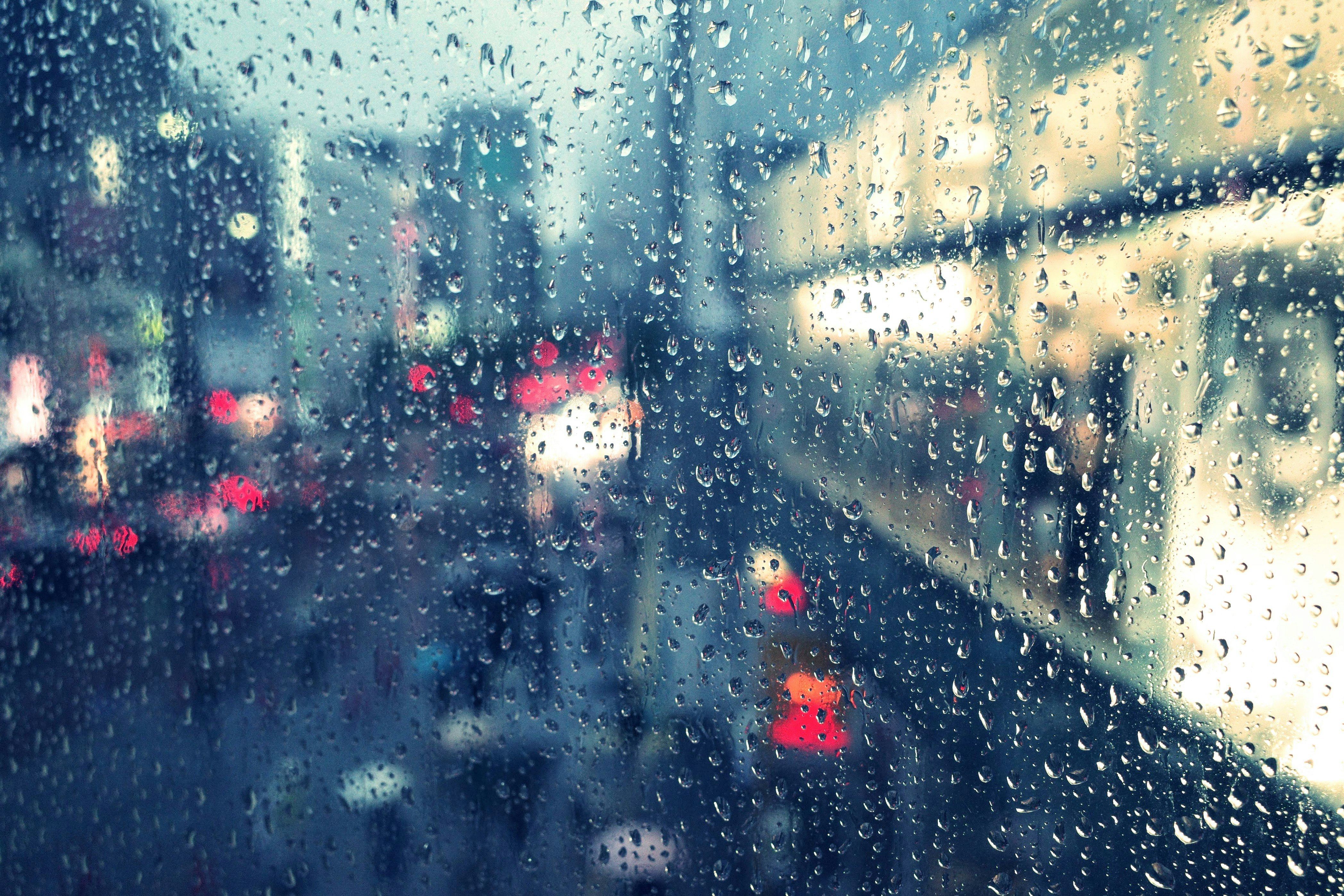 หยดฝนบนกระจกหน้าต่างมองเห็นถนนในเมือง