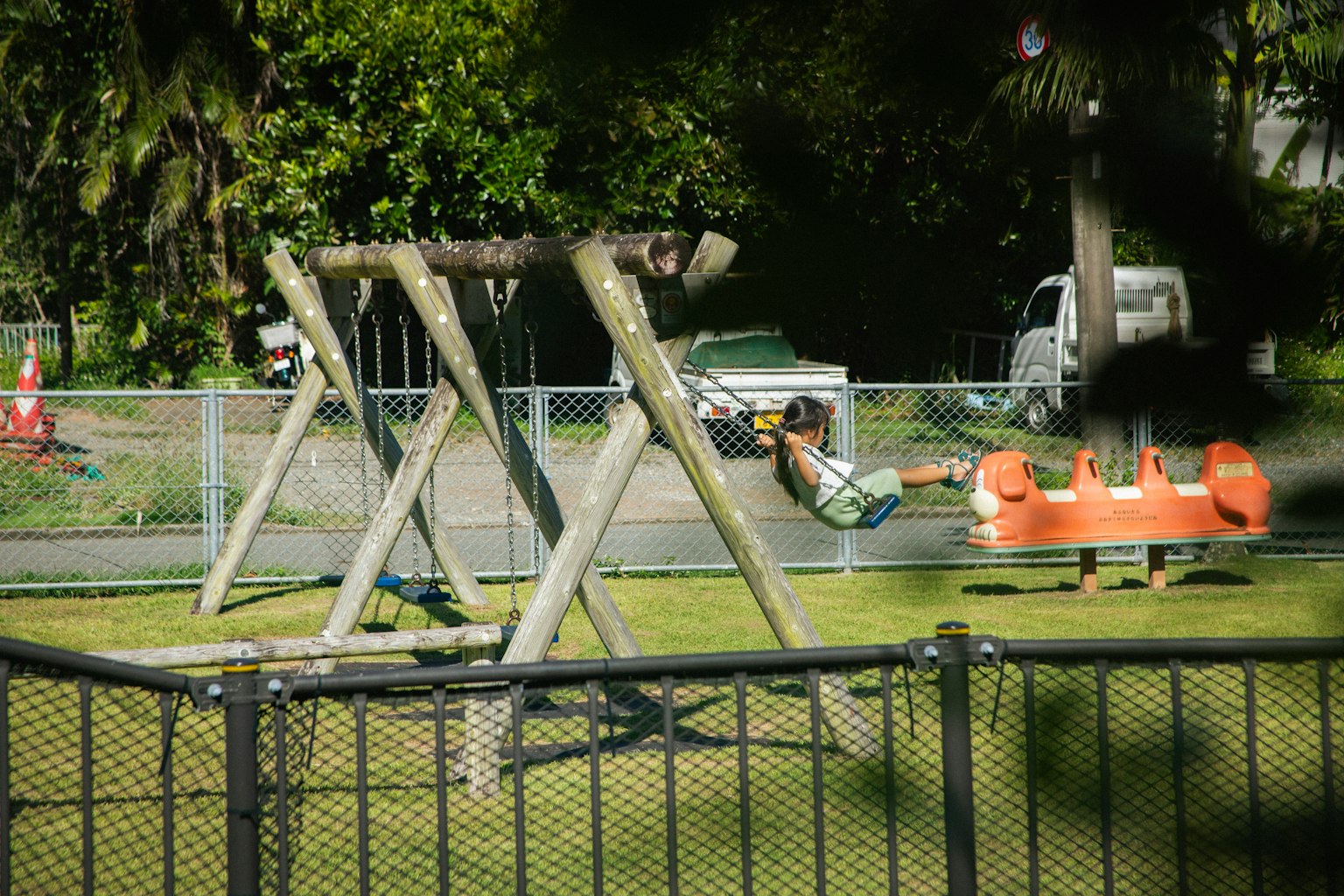 Enfant jouant sur une balançoire dans un parc avec de la verdure environnante