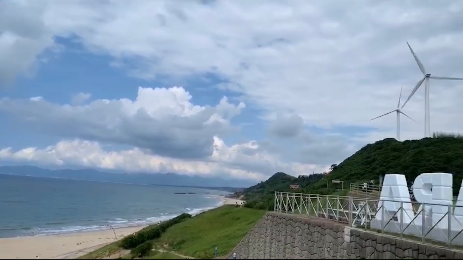 Vue panoramique de la côte avec des éoliennes et un ciel nuageux