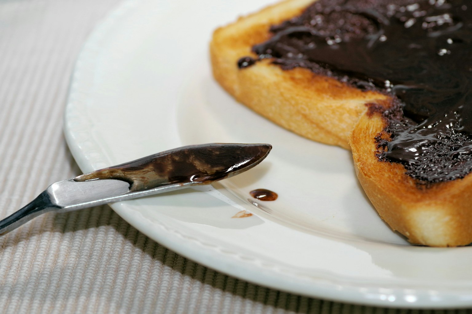 Hình ảnh bánh mì nướng phết kem chocolate với một cái thìa đặt trên đĩa