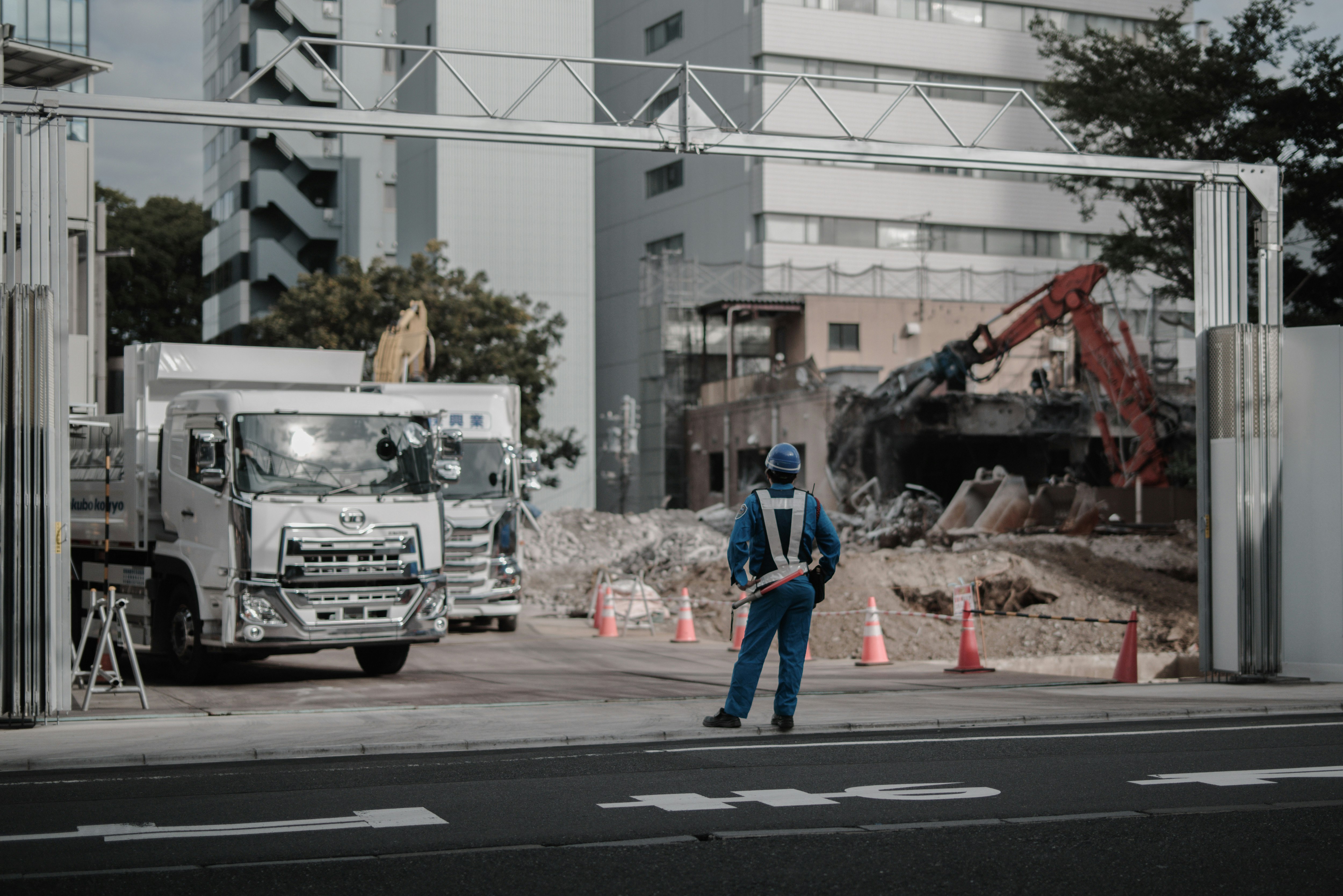再開発工事現場のトラックと重機が並ぶ道路沿い