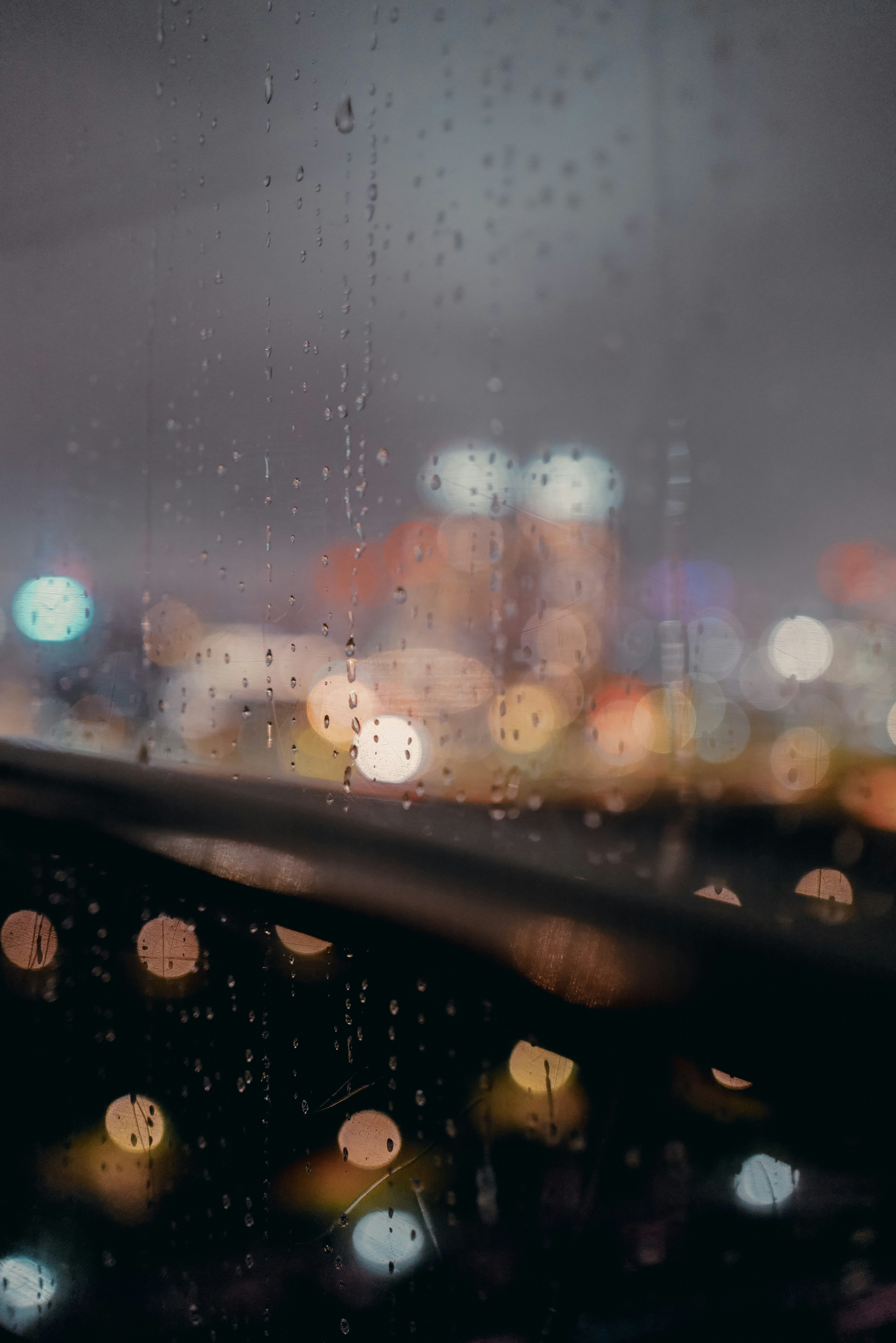 雨粒のついた窓越しににぎわう夜の街並み