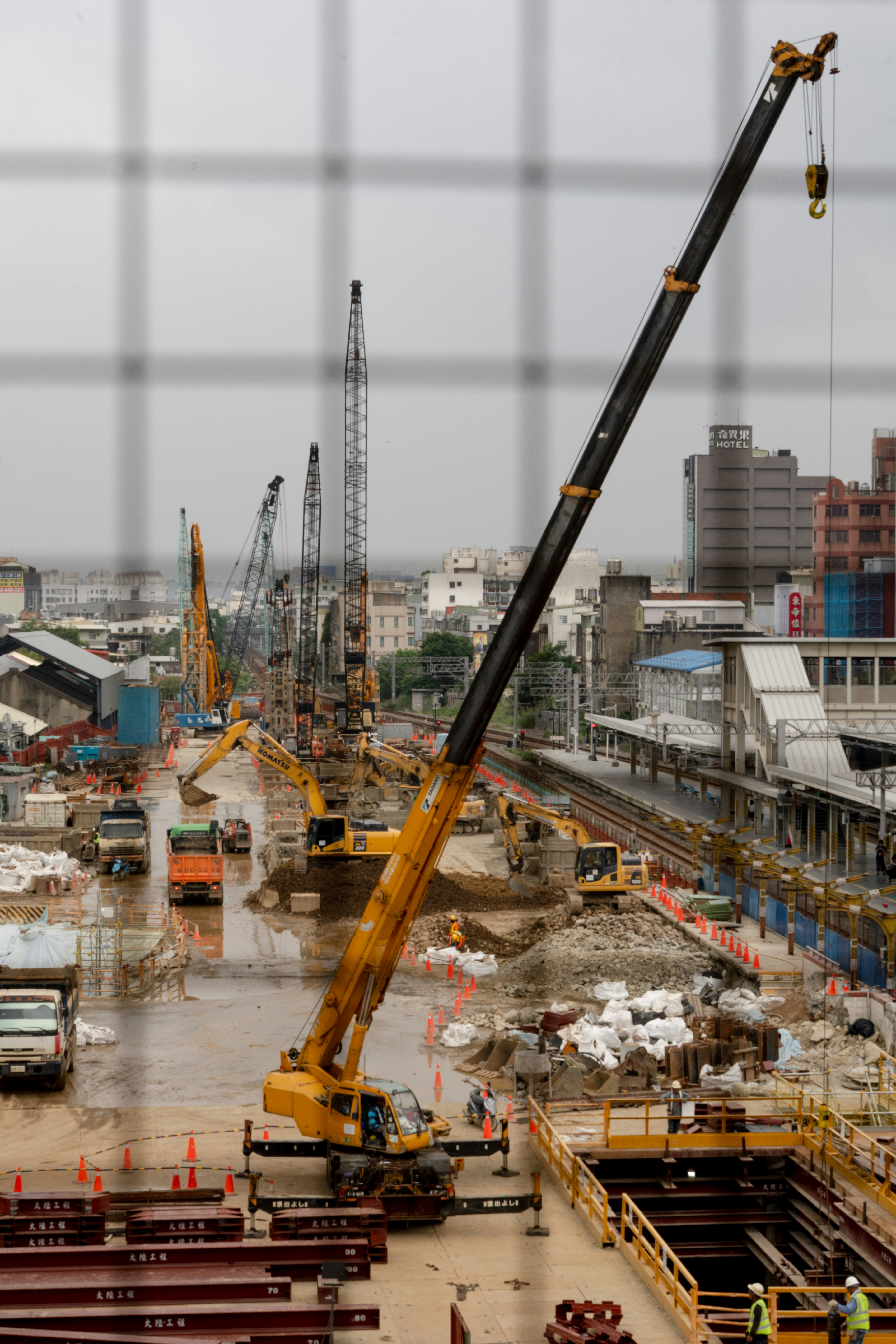 高層ビル街を背景にした工事現場のクレーンと作業車