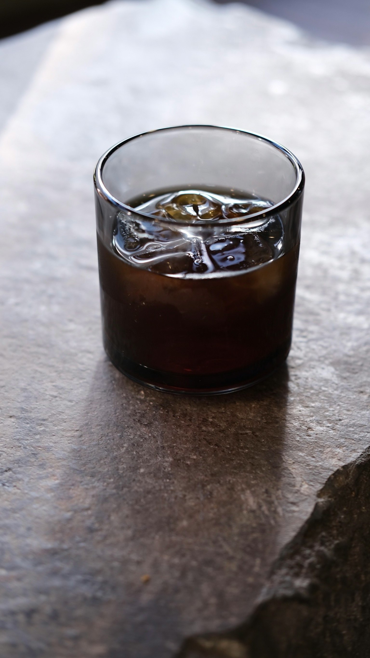 Một ly whisky có đá đặt trên bàn đá
