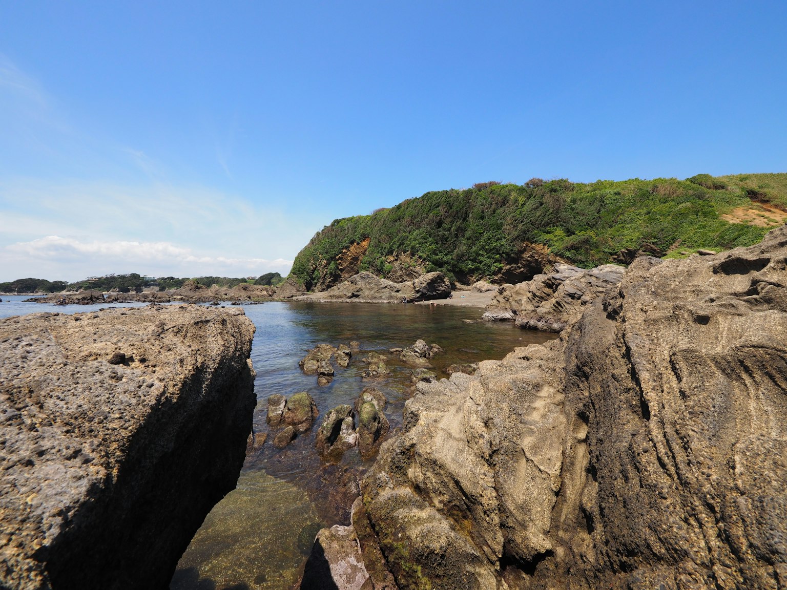 Paesaggio costiero roccioso con cielo blu e acqua che circonda le rocce