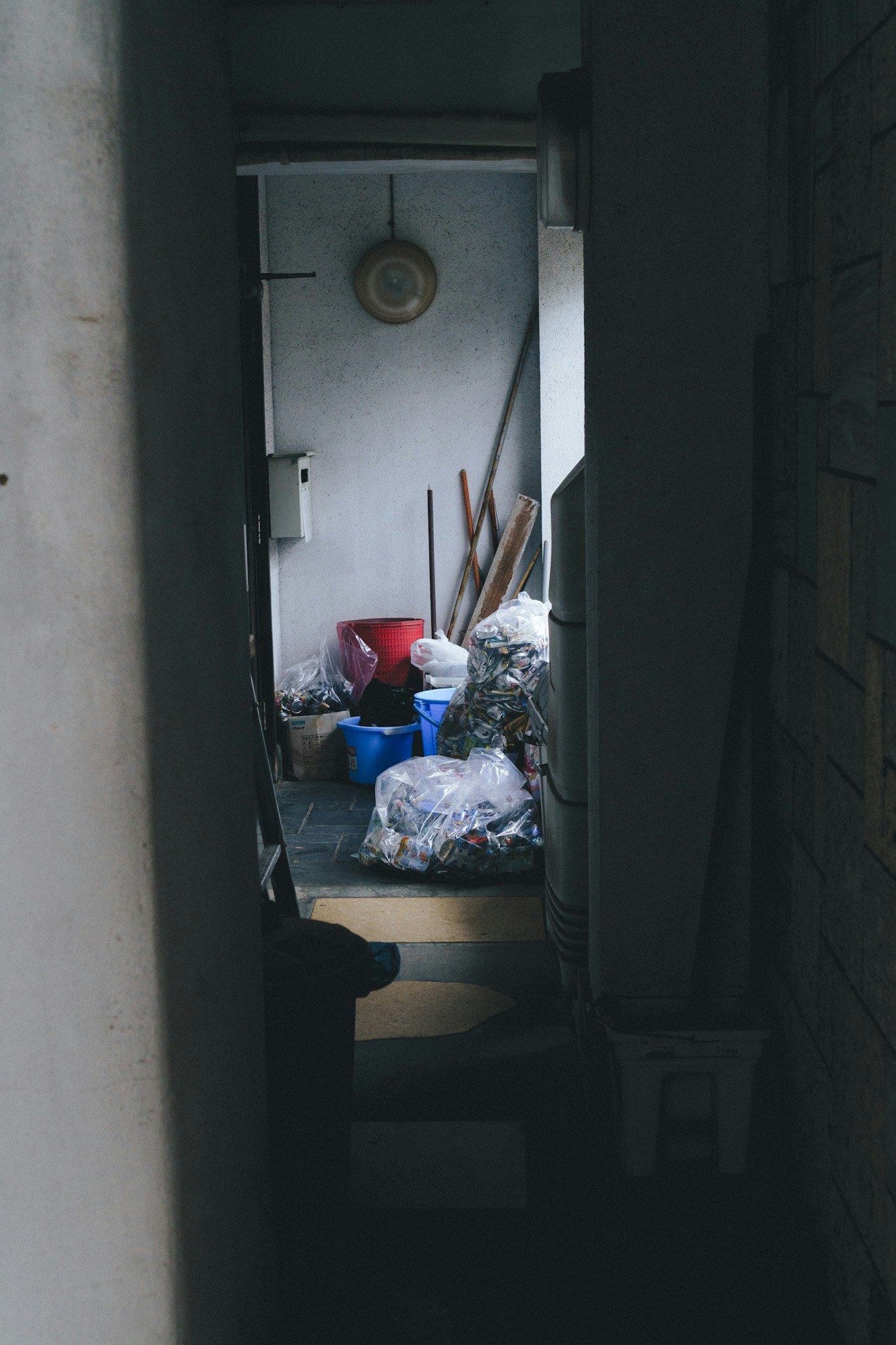 narrow alley passage with laundry and trash bags in the distance