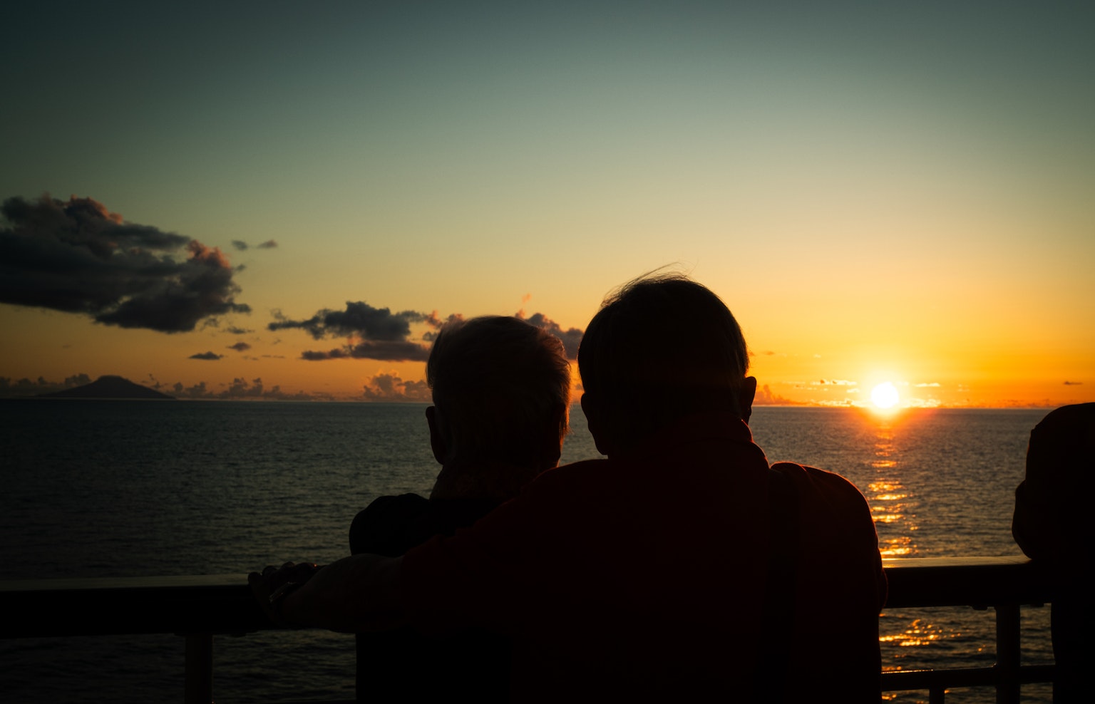 Silueta de dos personas mirando la puesta de sol sobre el océano