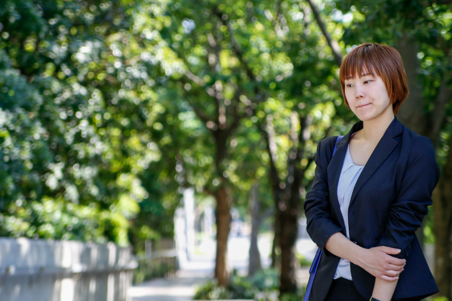 Une femme pensive en tenue professionnelle entourée de verdure