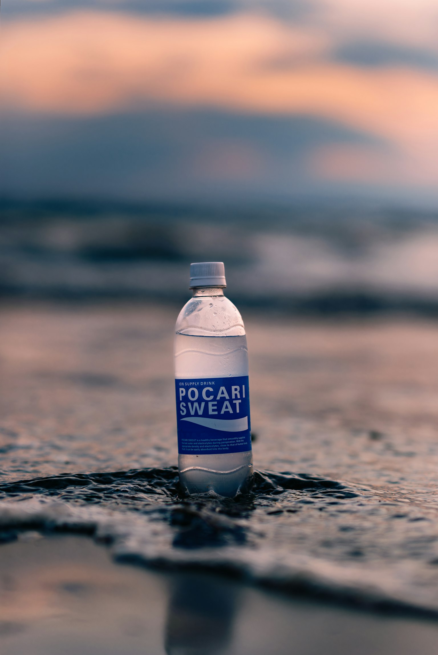 Une bouteille de boisson sportive dans les vagues avec un ciel au coucher du soleil