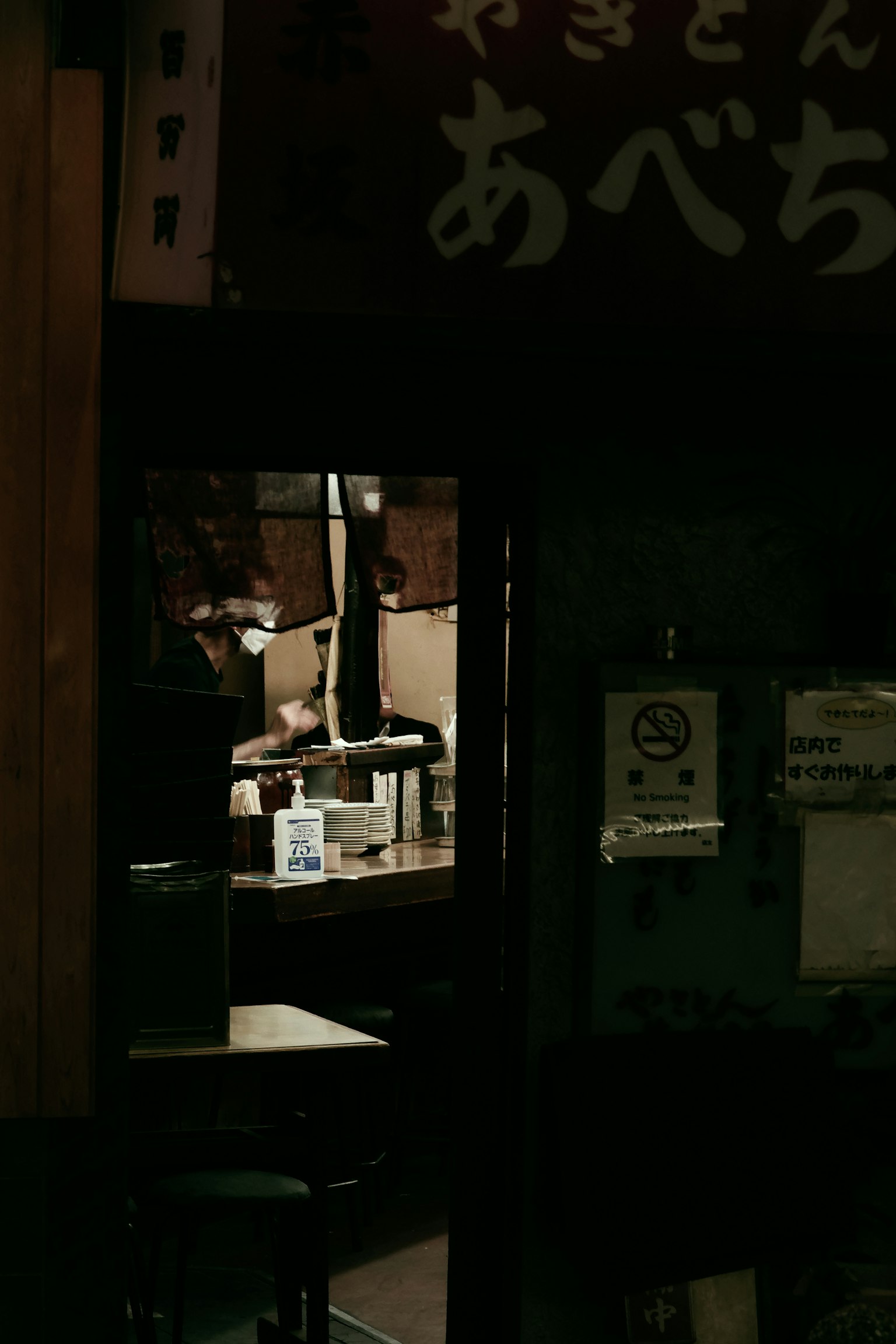 Nội thất của một izakaya tối với nhân viên đang nấu ăn