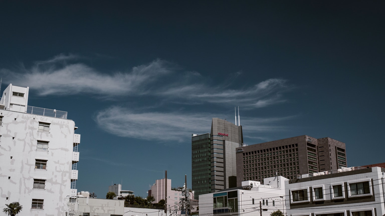 City skyline with wispy clouds against a blue sky