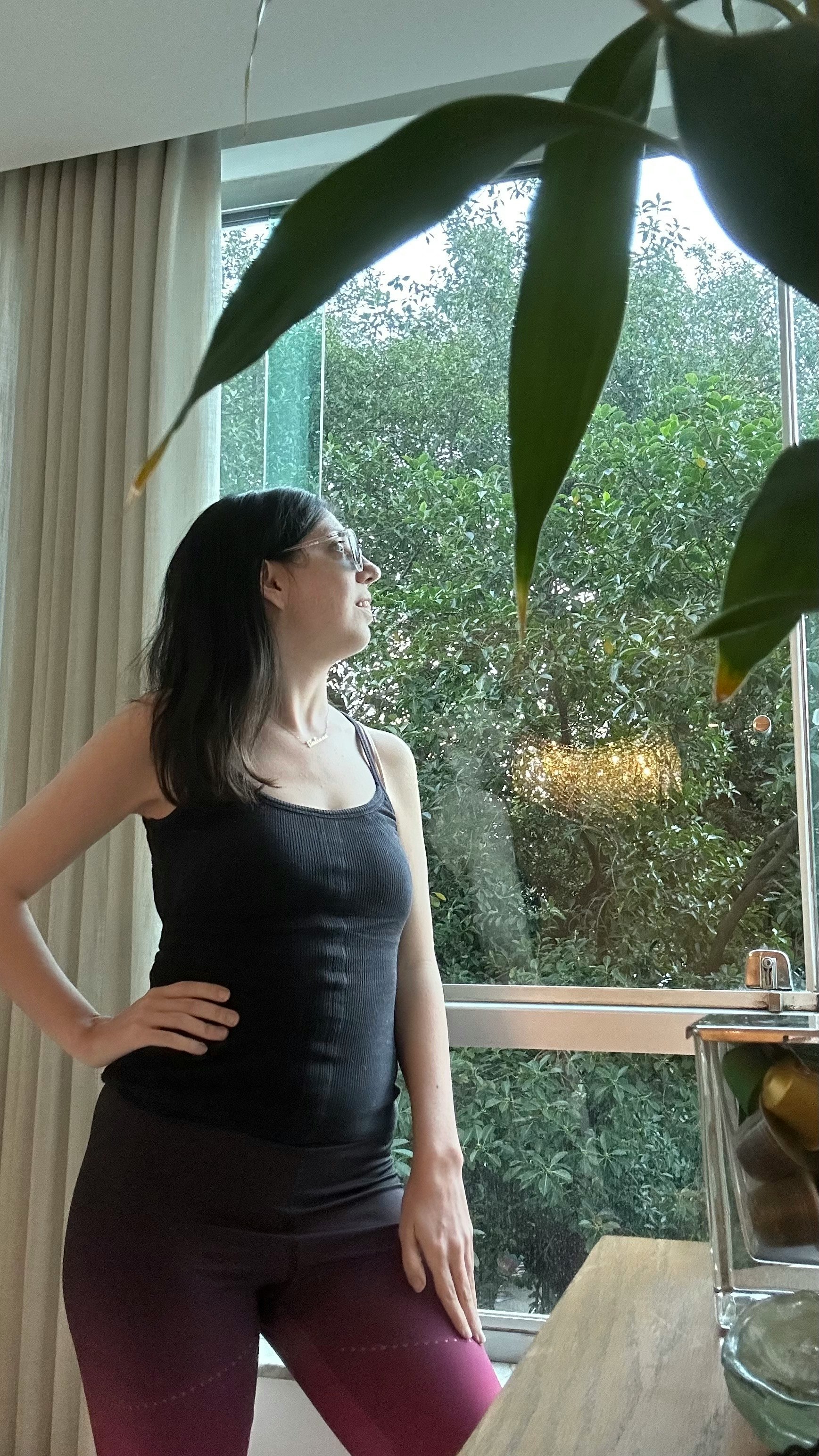 窗邊穿黑色無袖上衣的女性望向窗外綠意