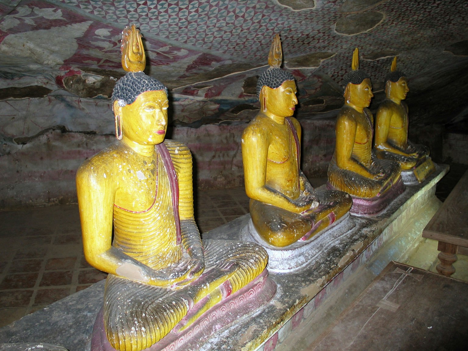 Scene featuring golden Buddha statues arranged in a cave