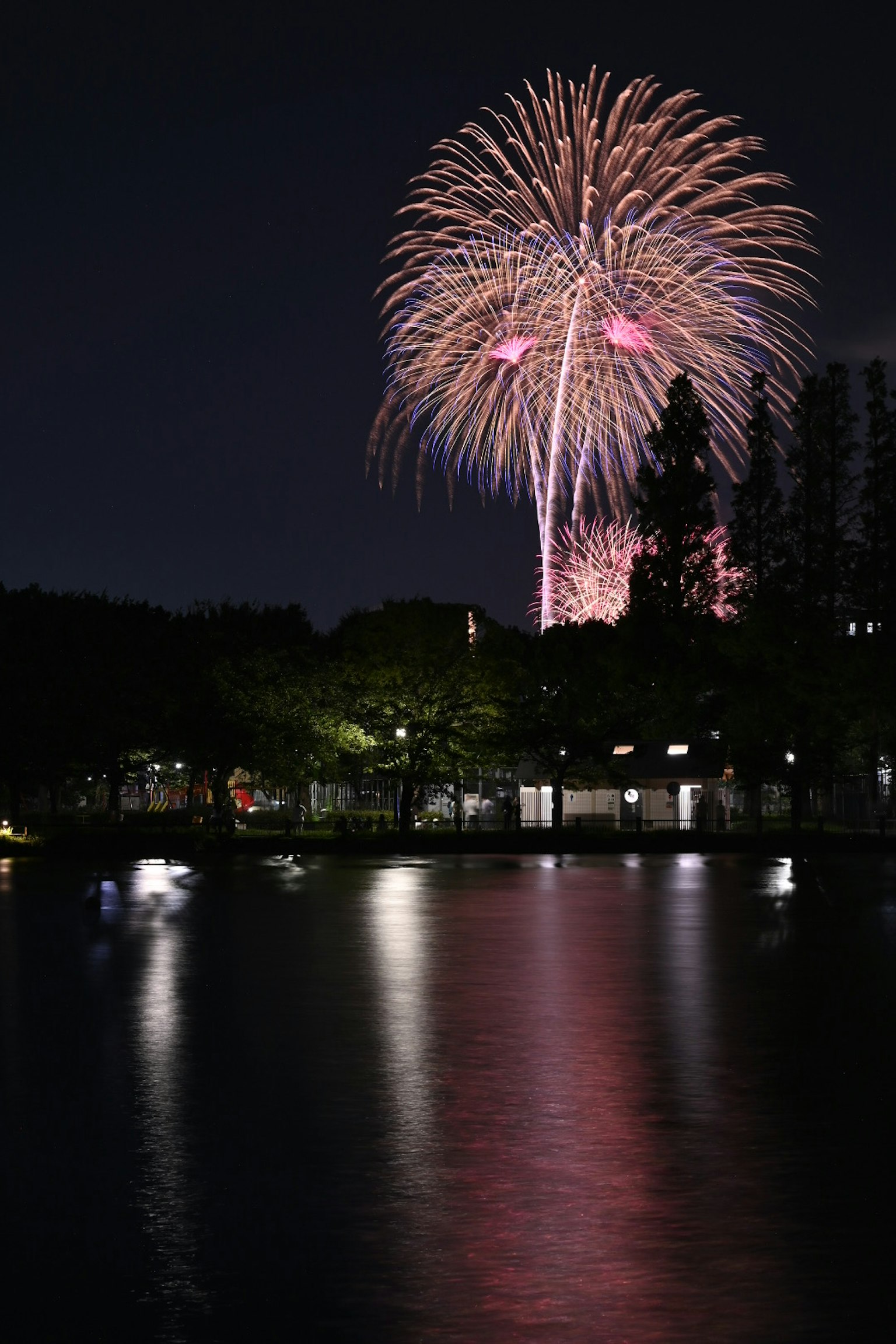 Colorful fireworks bursting in the night sky reflected on a calm lake