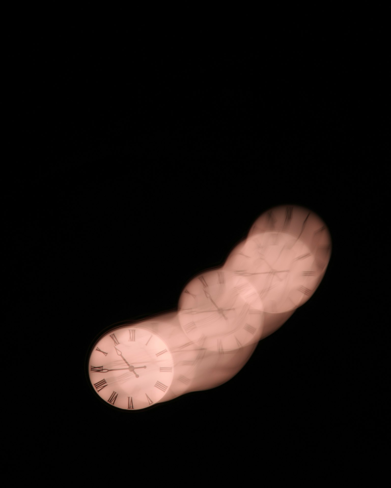 黒い背景に浮かぶぼやけた時計の画像
