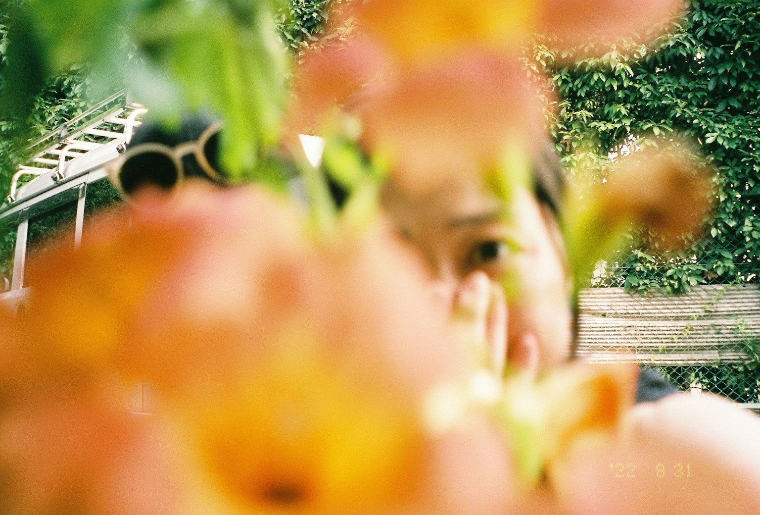 흐릿한 오렌지 꽃 뒤에 부분적으로 보이는 사람의 얼굴