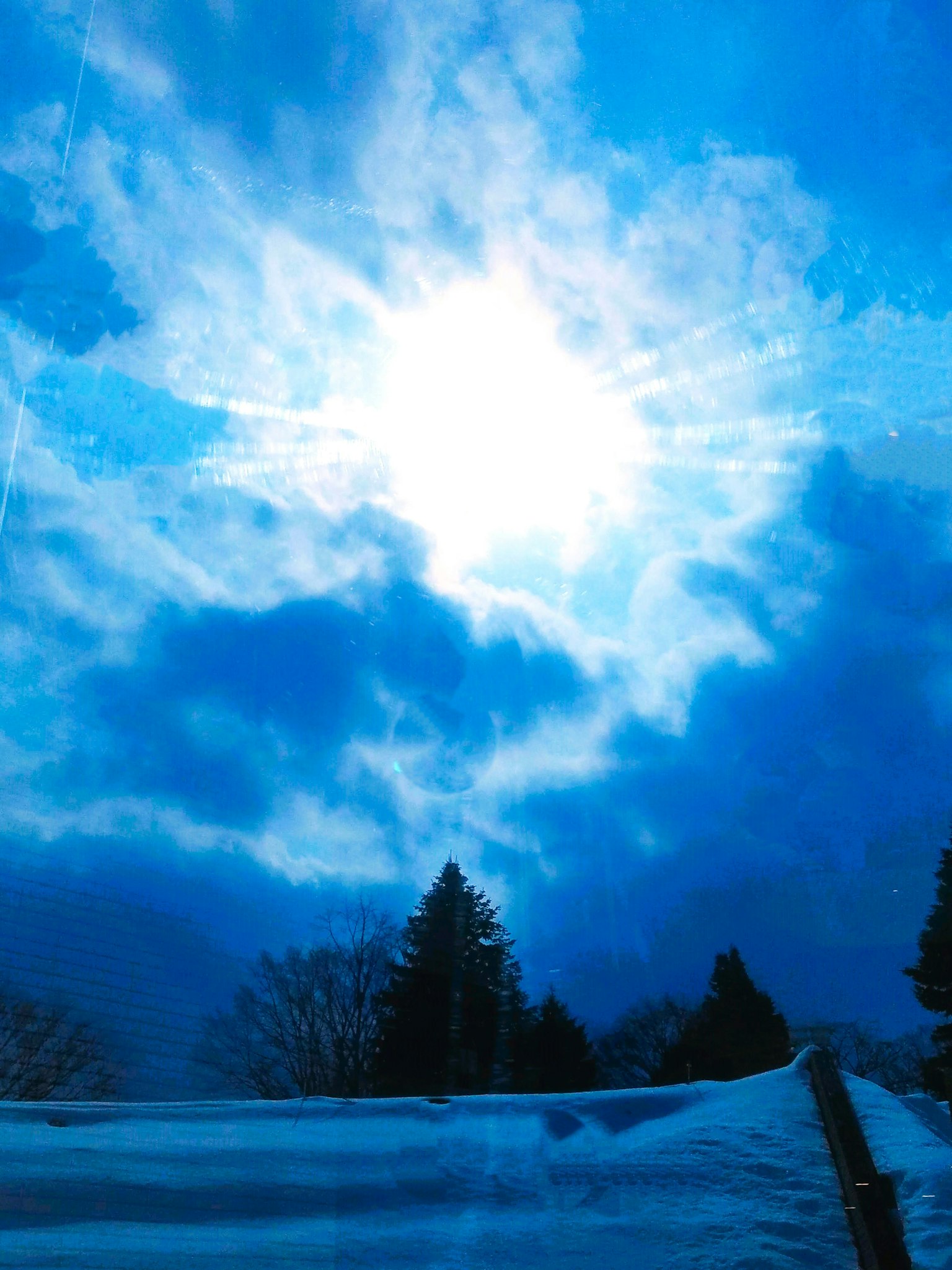 Sole luminoso che brilla attraverso un cielo blu e nuvole bianche