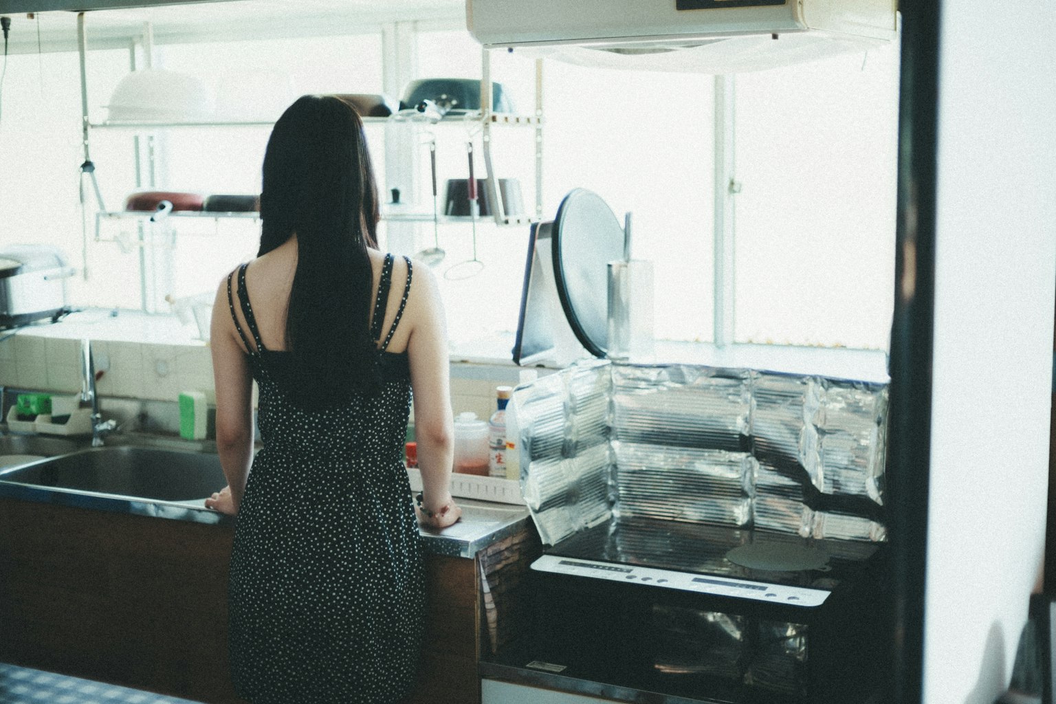Una mujer de pie en una cocina de espaldas