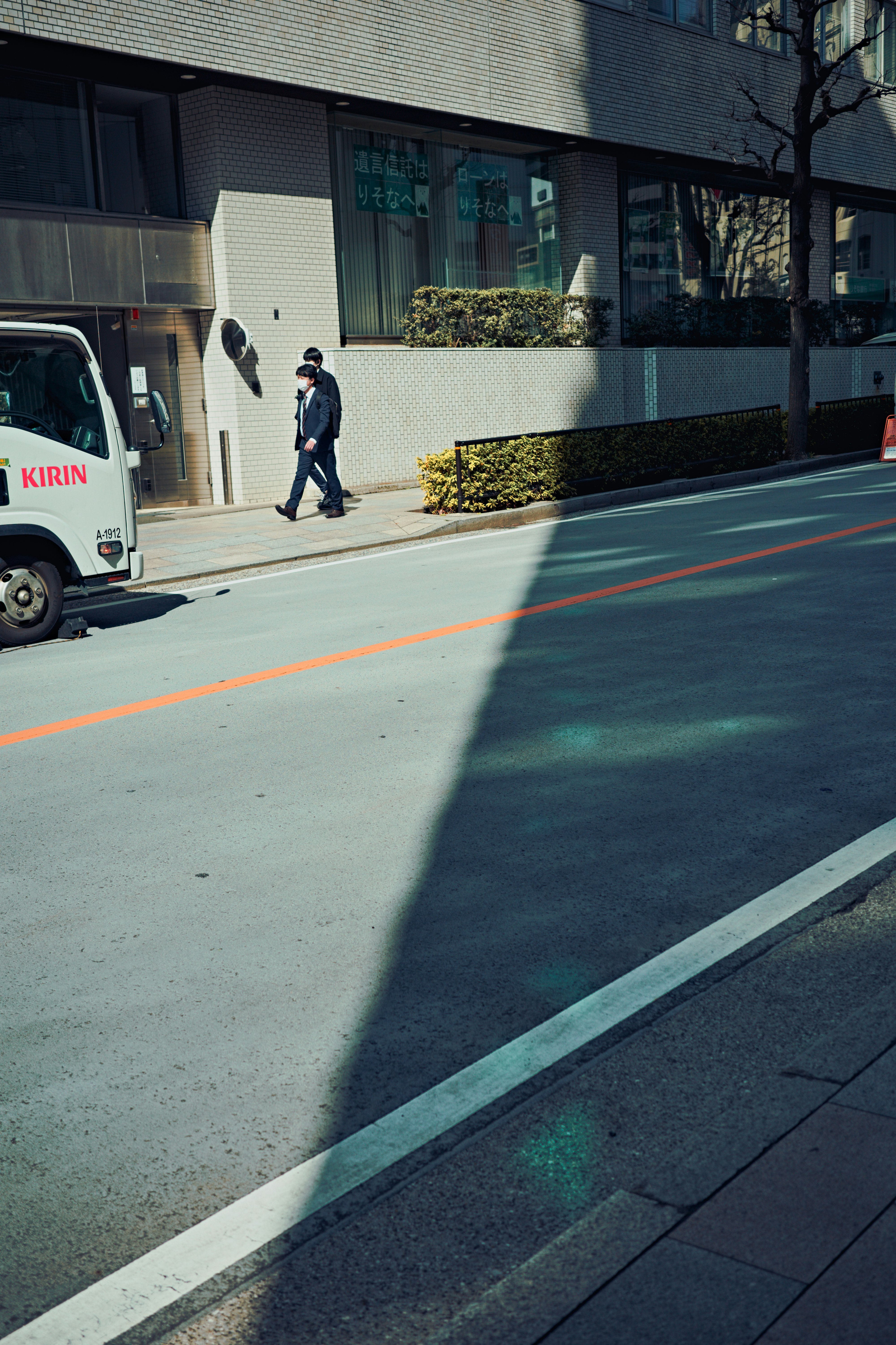 Businessman walking on urban street with contrasting shadows