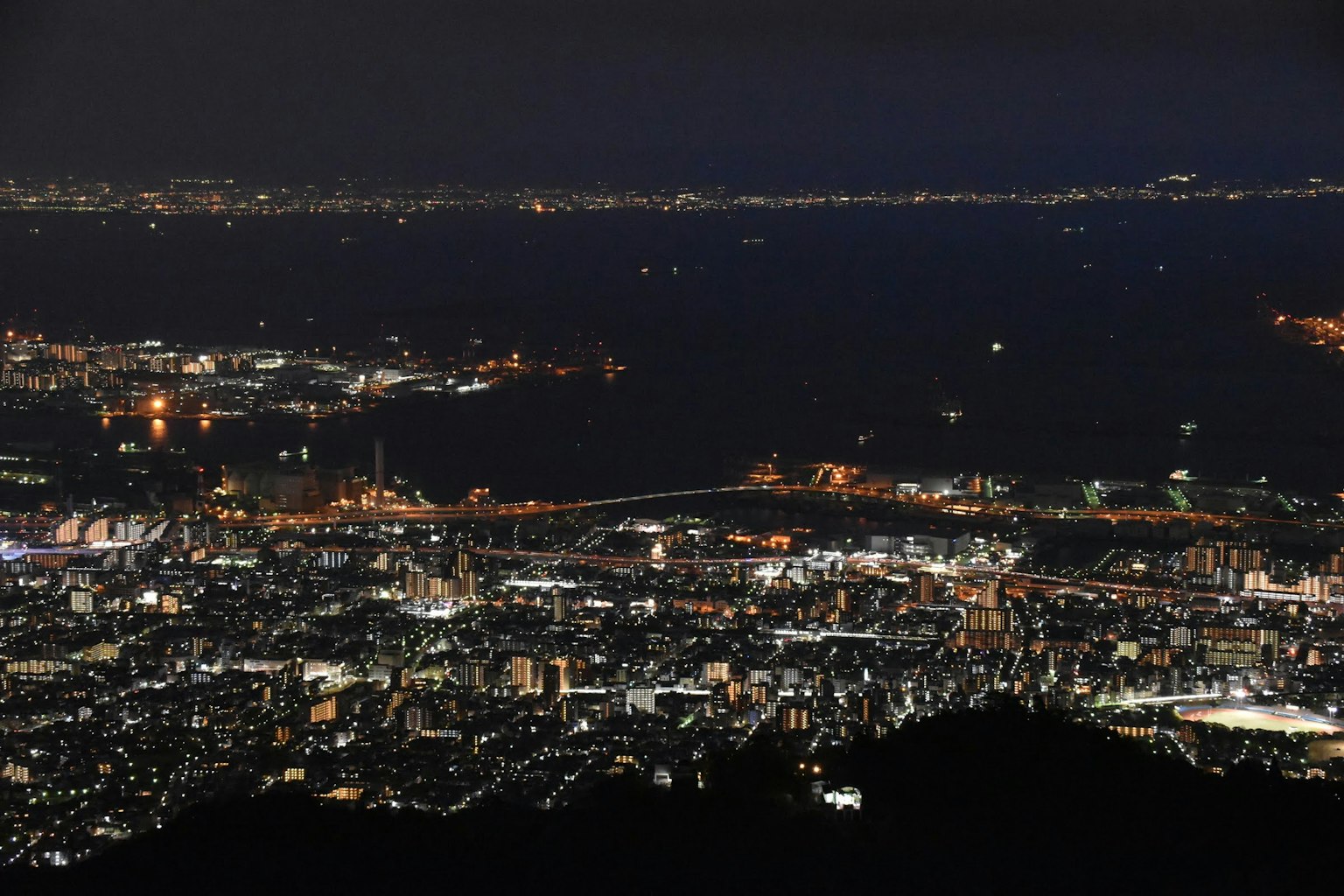 Vista nocturna de una ciudad con edificios iluminados y un puerto