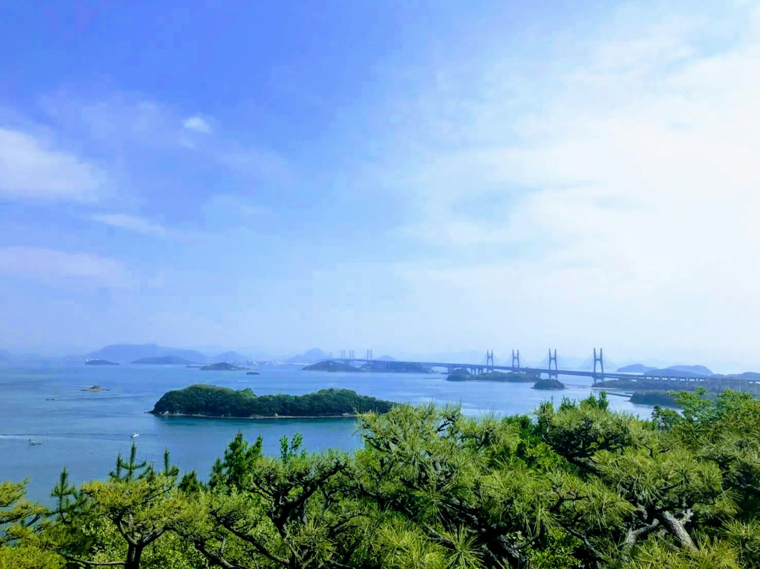 Scenic view of islands surrounded by blue sky and sea with a visible bridge