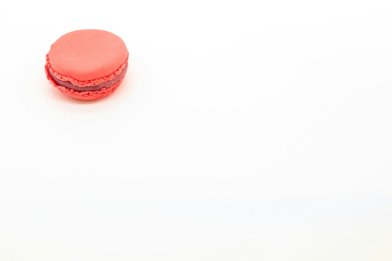 Un macaron rosso vivace su uno sfondo bianco